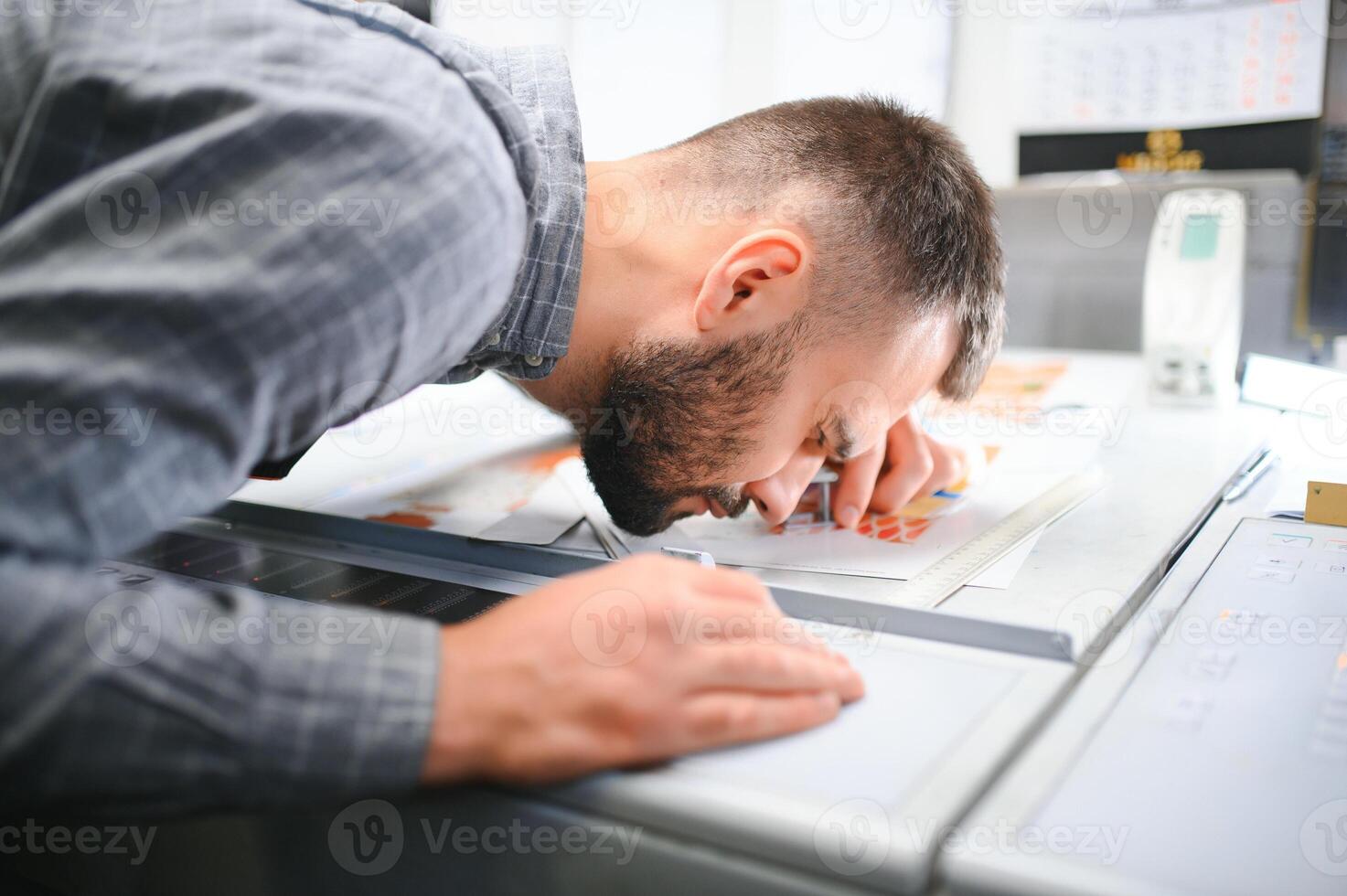 Graphic engineer or worker checking imprint quality in modern print shop photo