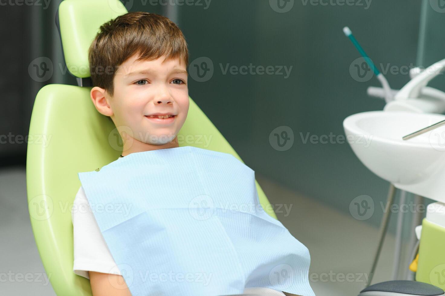 sorprendido pequeño chico sentado en el del dentista silla foto