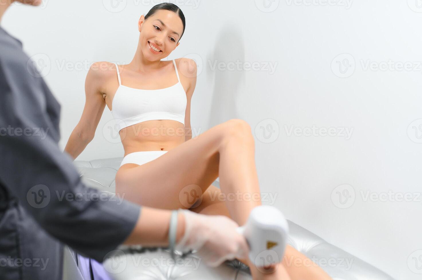 Laser epilation and cosmetology in beauty salon. Beautiful brunette woman getting hair removing on legs photo