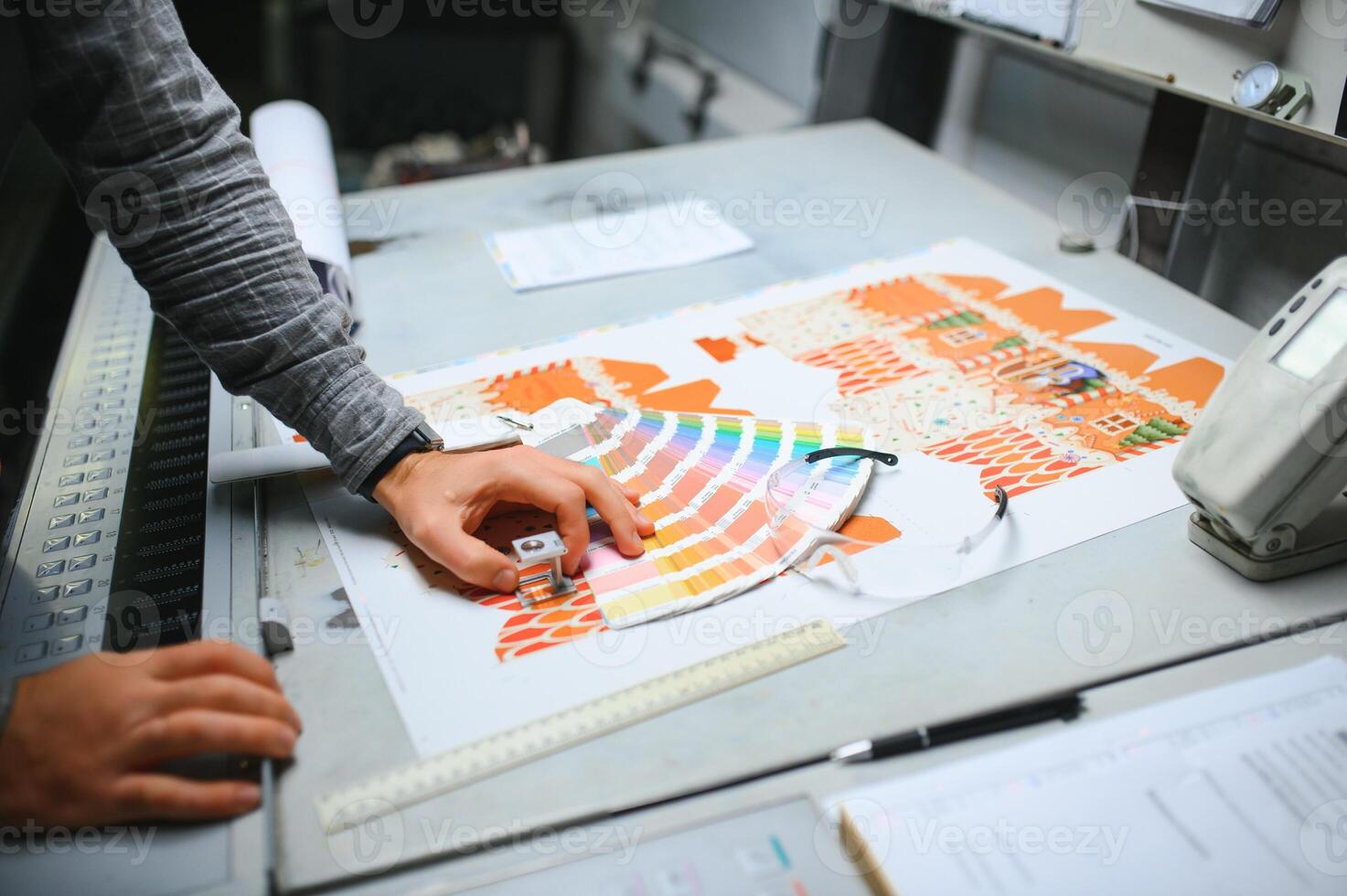 Print house worker controlling printing process quality and checking colors with magnifying glass photo