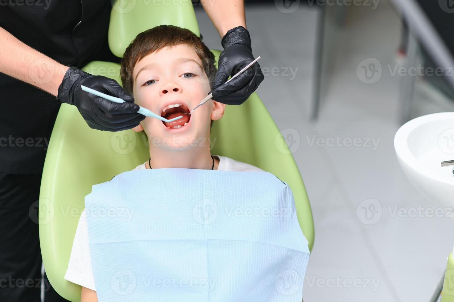 Dentist examining little boy's teeth in clinic photo