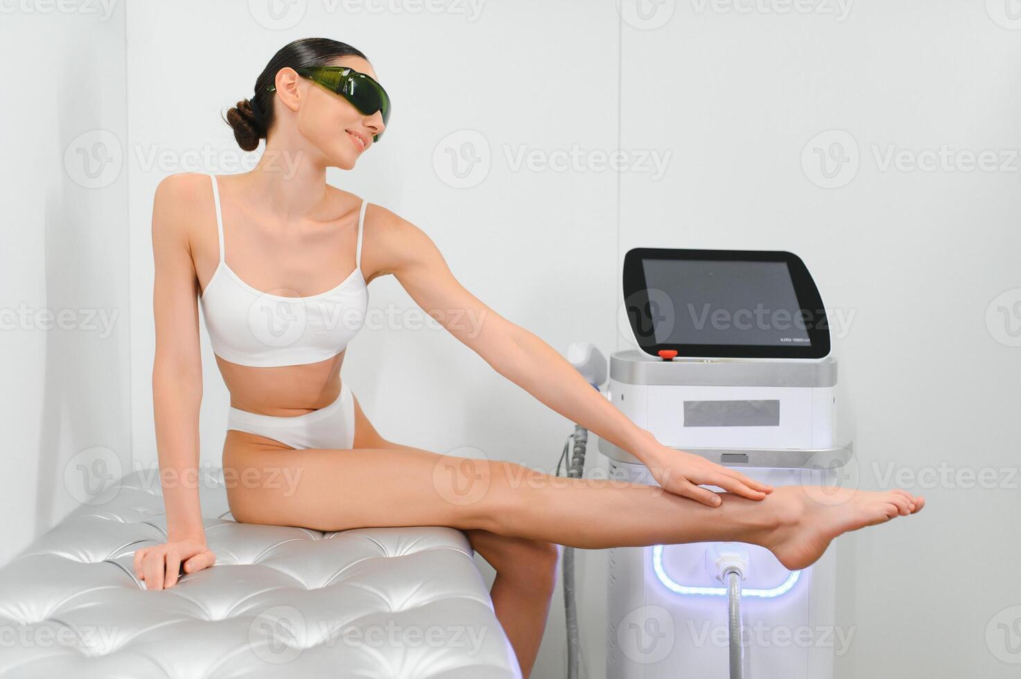 Young beautiful woman with laser hair removal machine in cosmetology cabinet photo