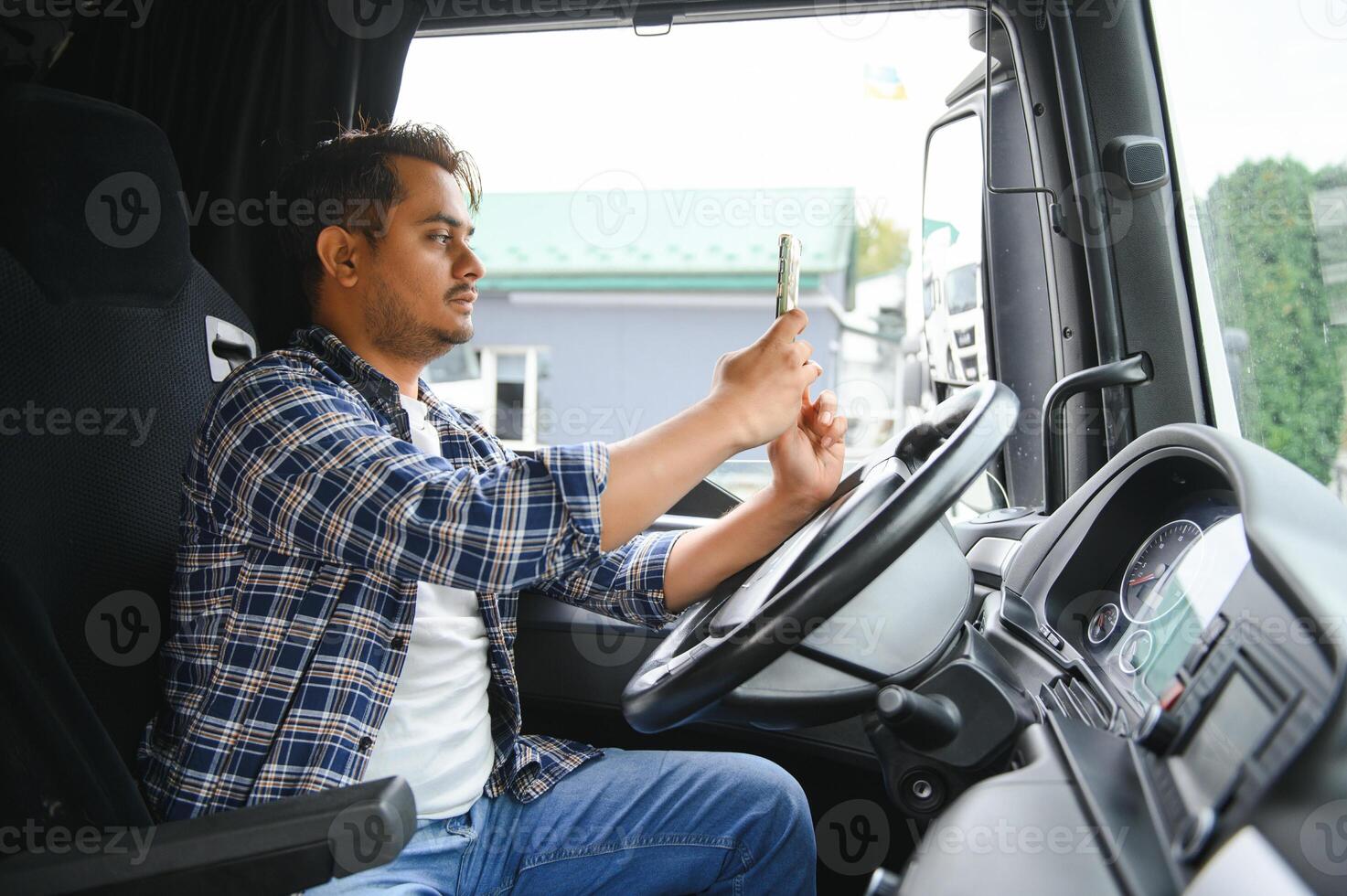 Young handsome indian man truck driver using smart phone photo