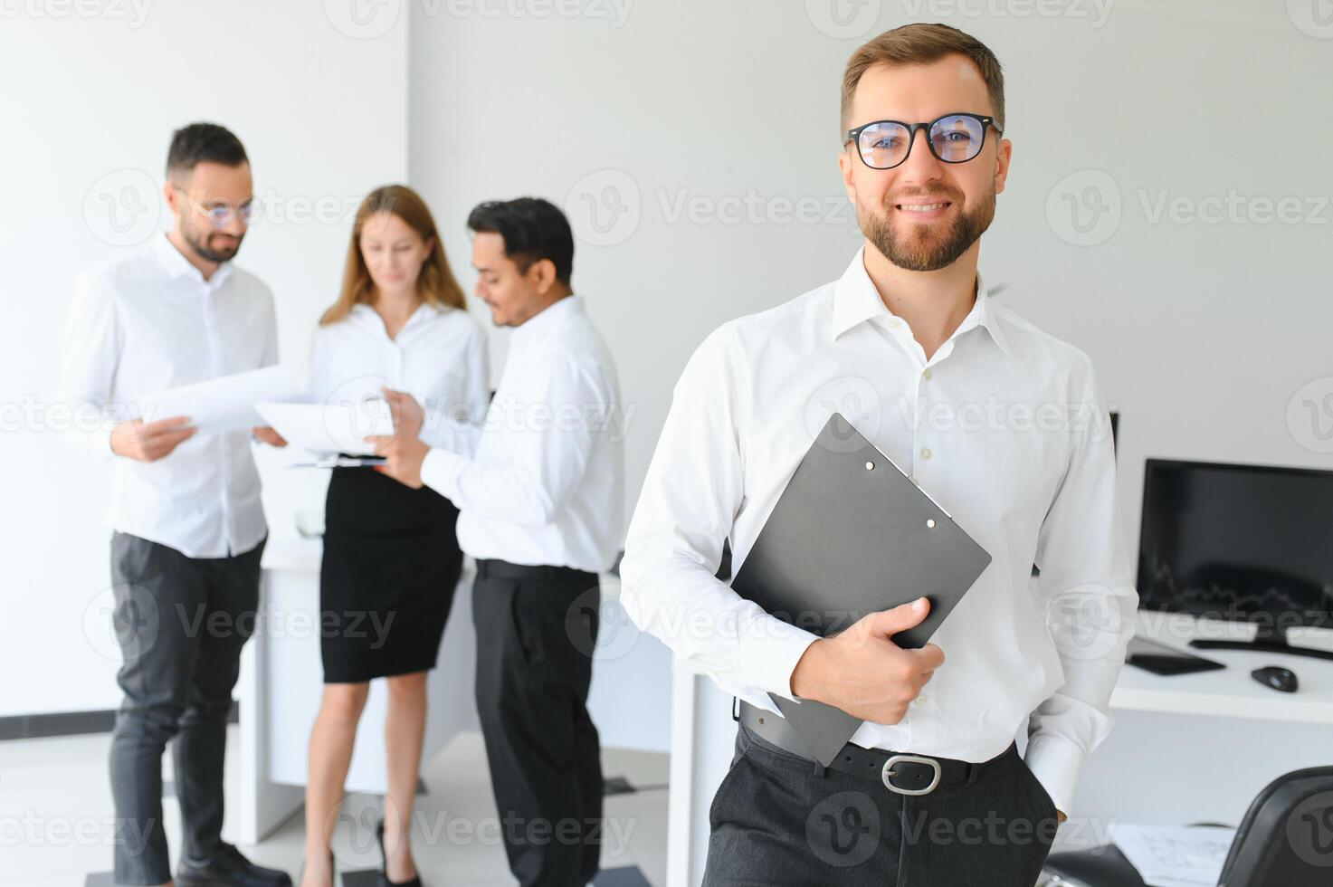 retrato de joven hermoso empresario en oficina con colegas en el antecedentes foto