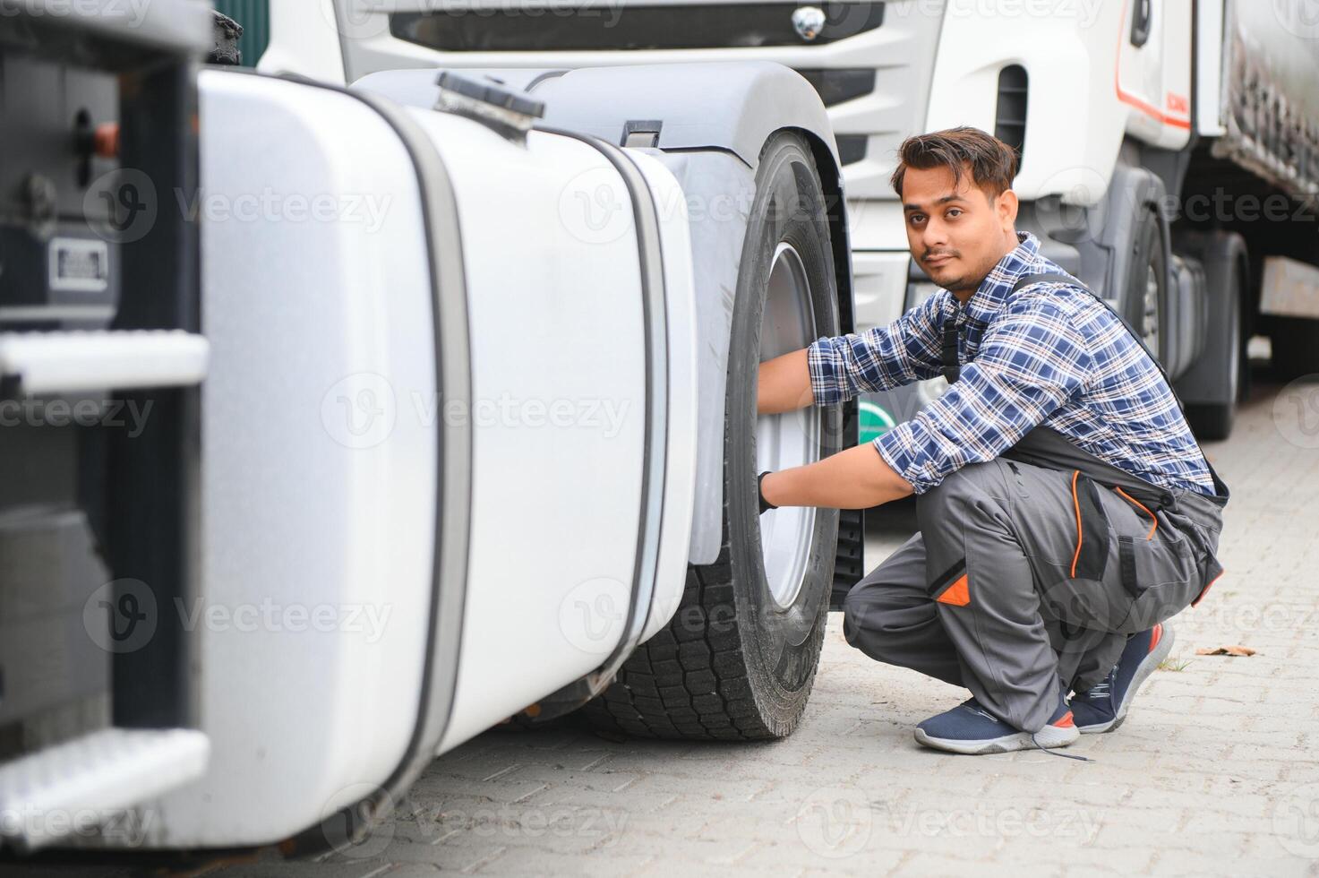 Indian Mechanic unscrews wheel truck pneumatic wrench photo