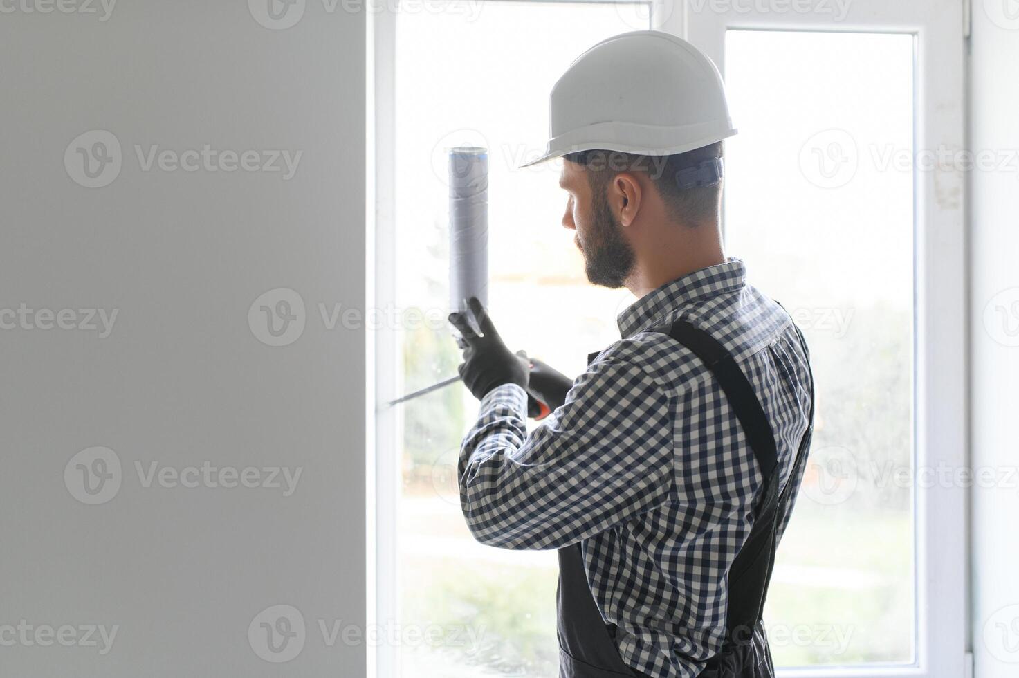 Side View Of A Young Male Worker Applying Glue With Silicone Gun photo