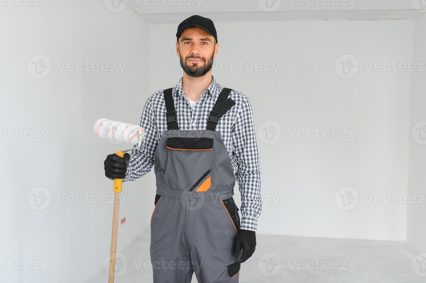 joven profesional trabajador en uniforme en pie con pintar rodillo. foto