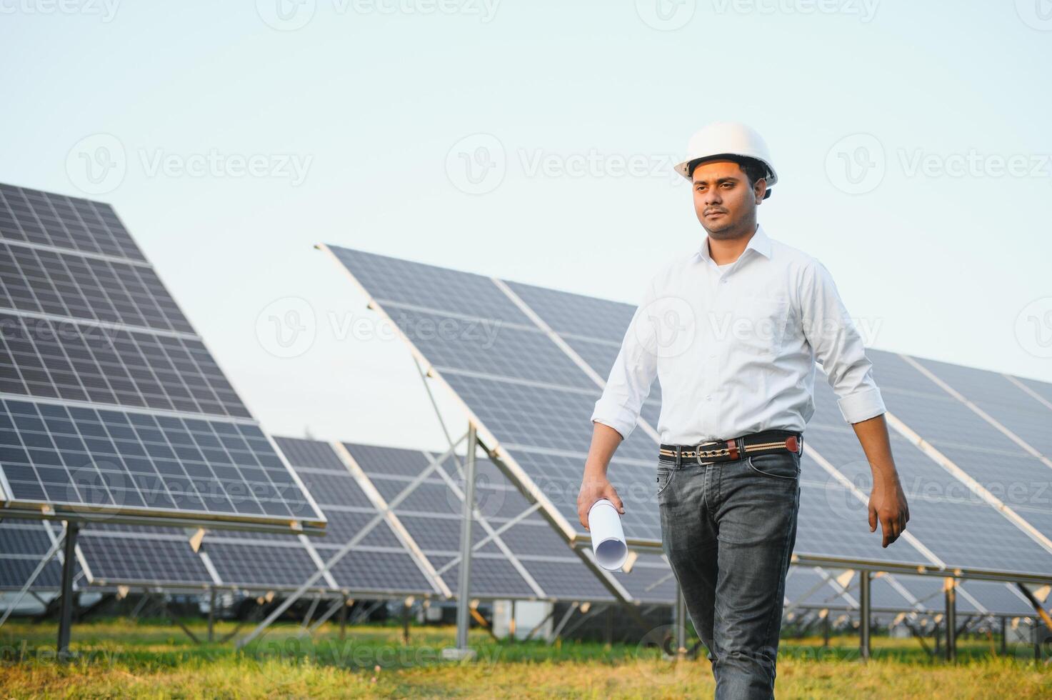 Portrait of Young indian male engineer standing near solar panels, with clear blue sky background, Renewable and clean energy. skill india, copy space photo