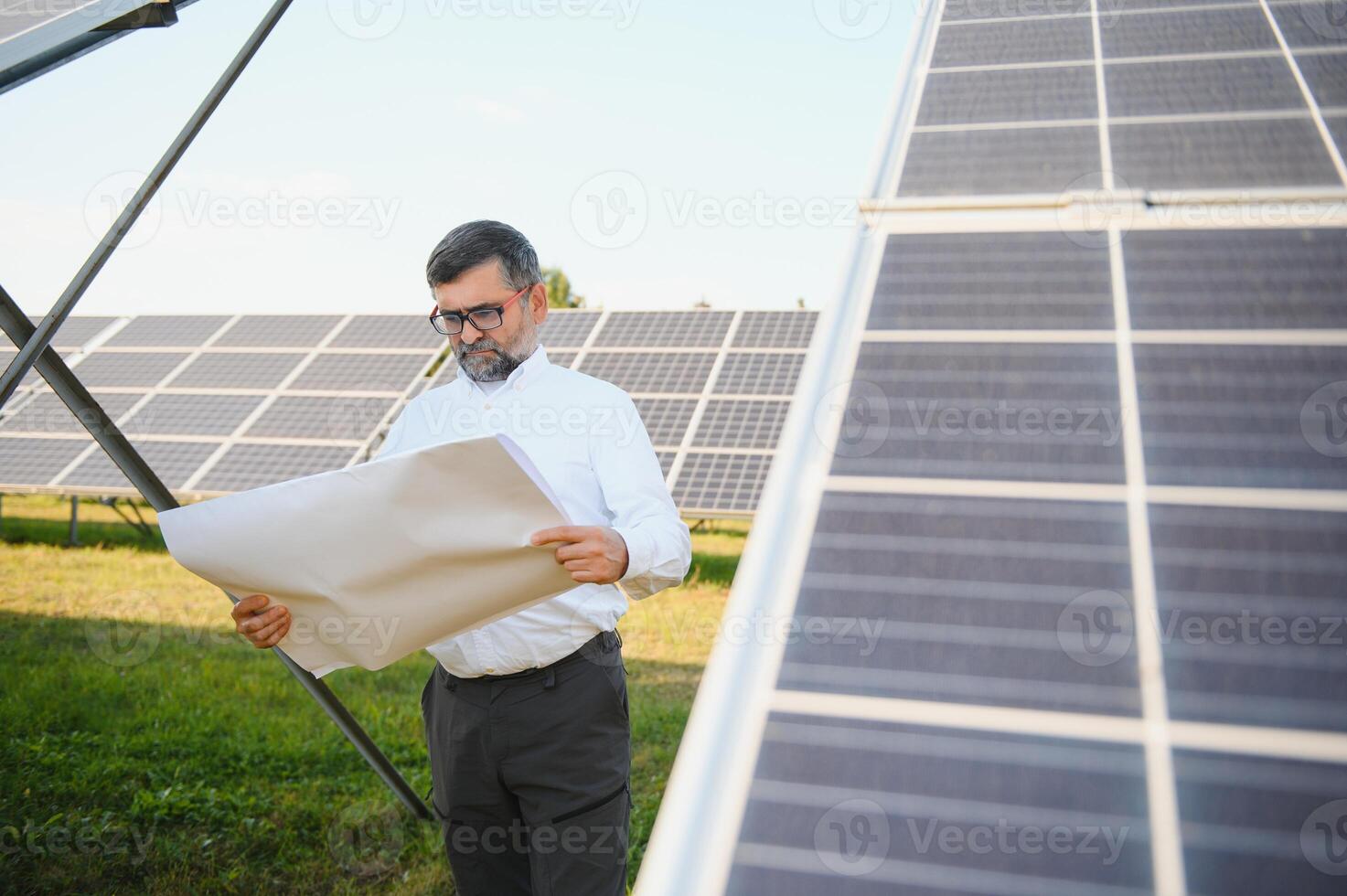 Solar power plant. Man standing near solar panels. Renewable energy photo