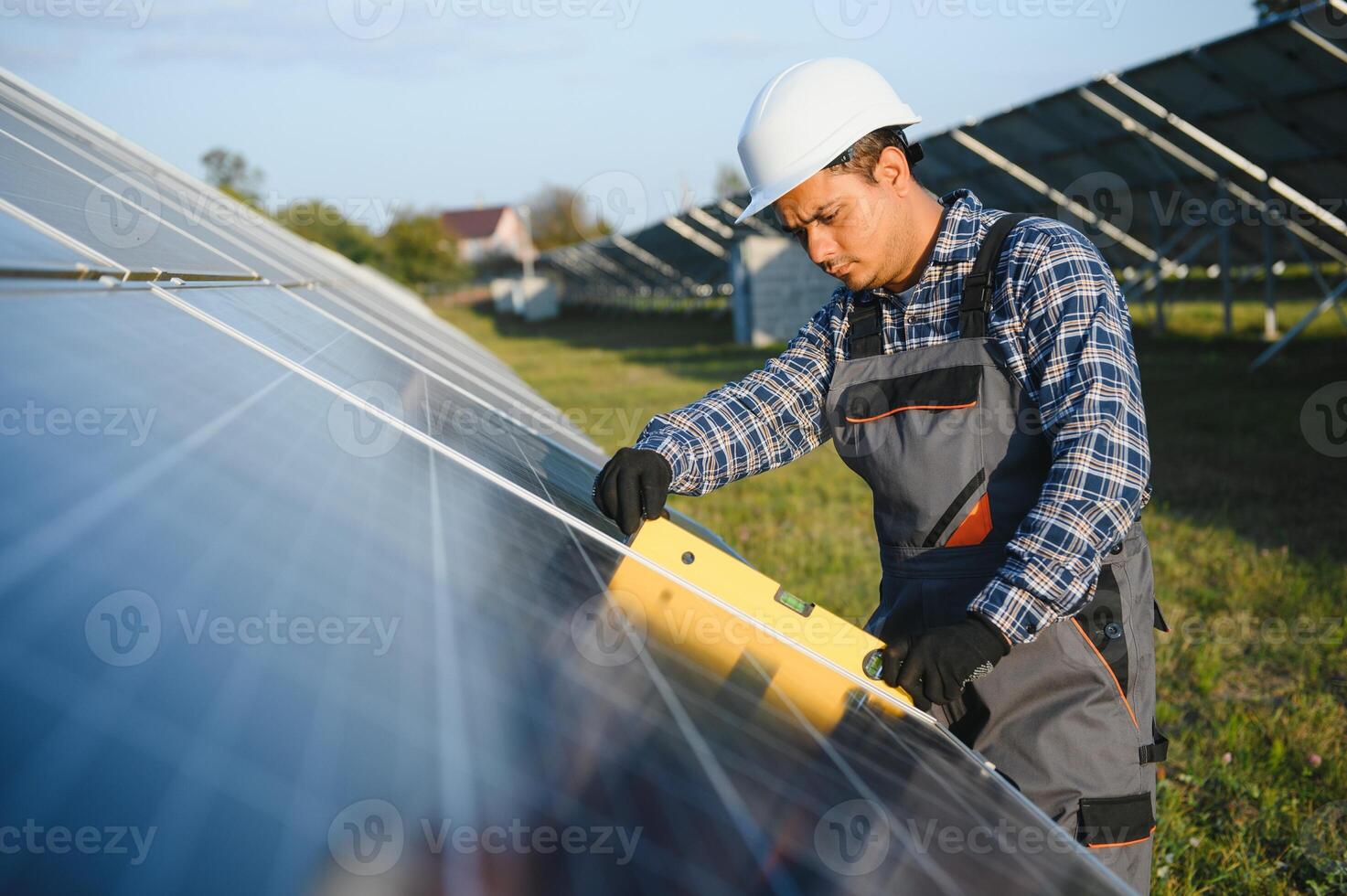 An Indian male worker is working on installing solar panels in a field photo