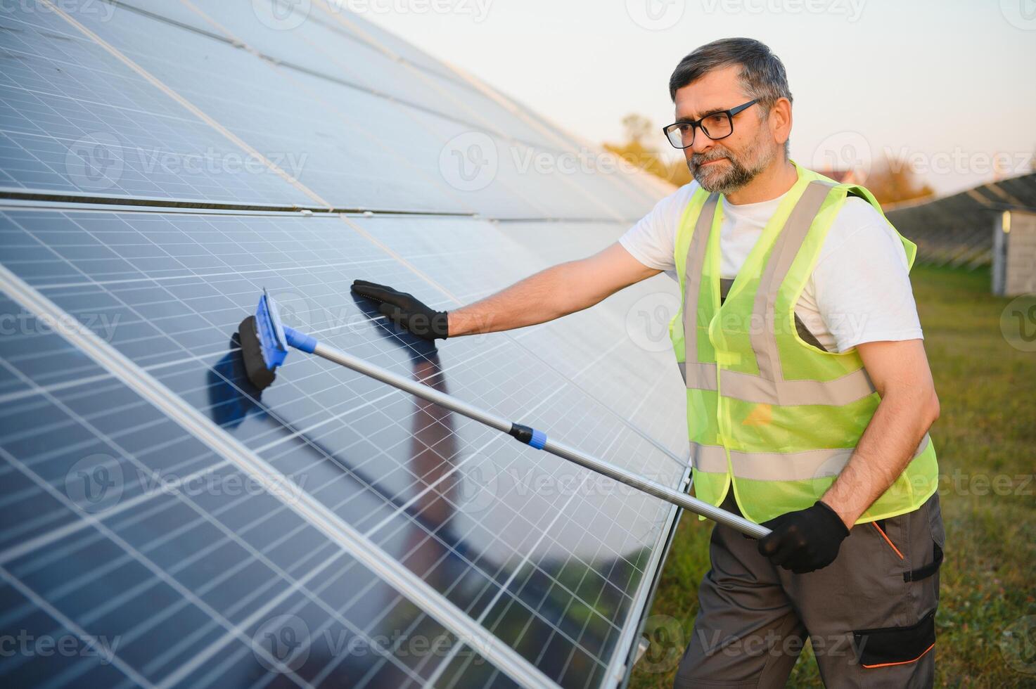 Worker cleaning solar panels after installation outdoors. photo