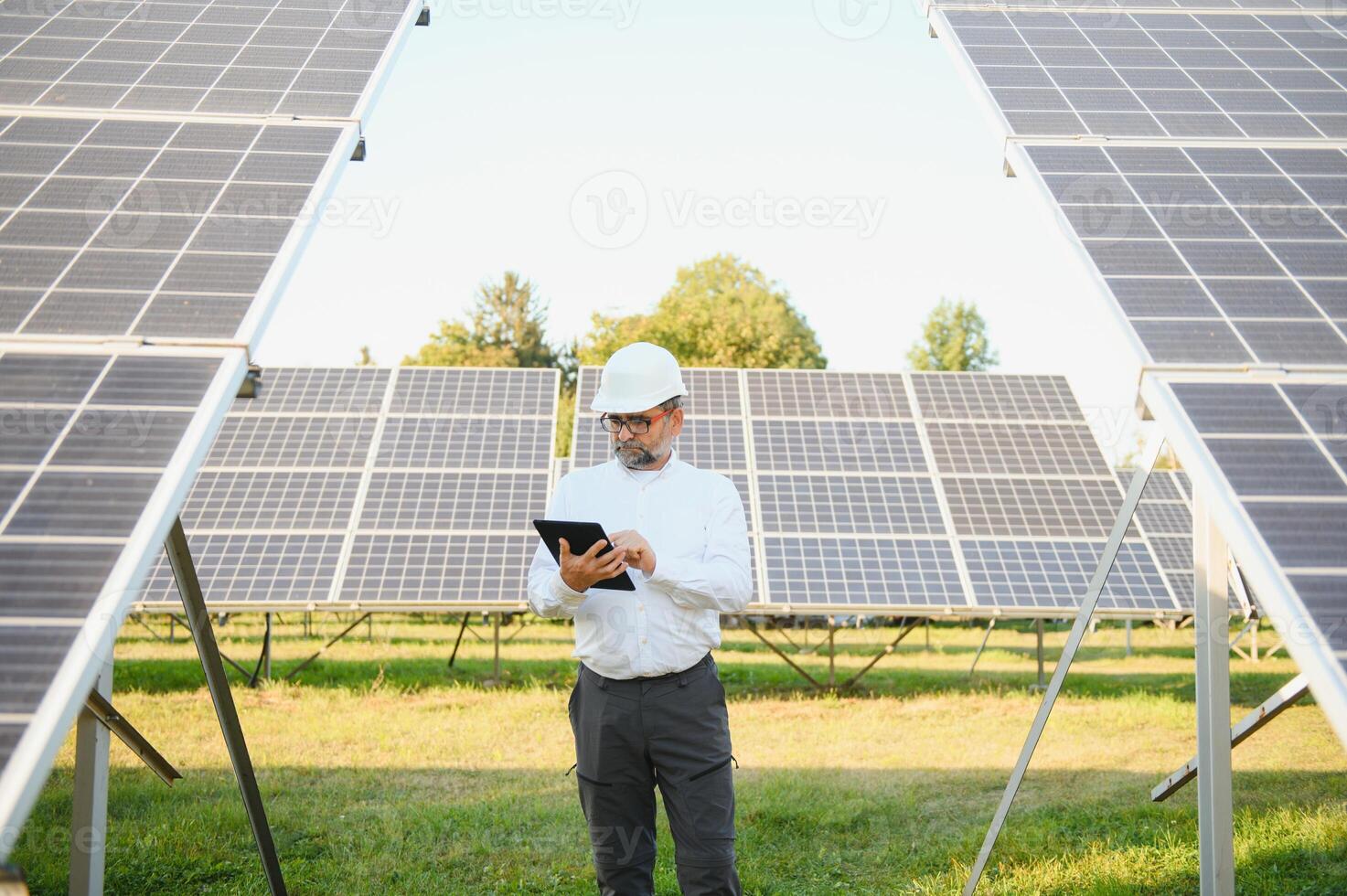 Solar power plant. Man standing near solar panels. Renewable energy photo