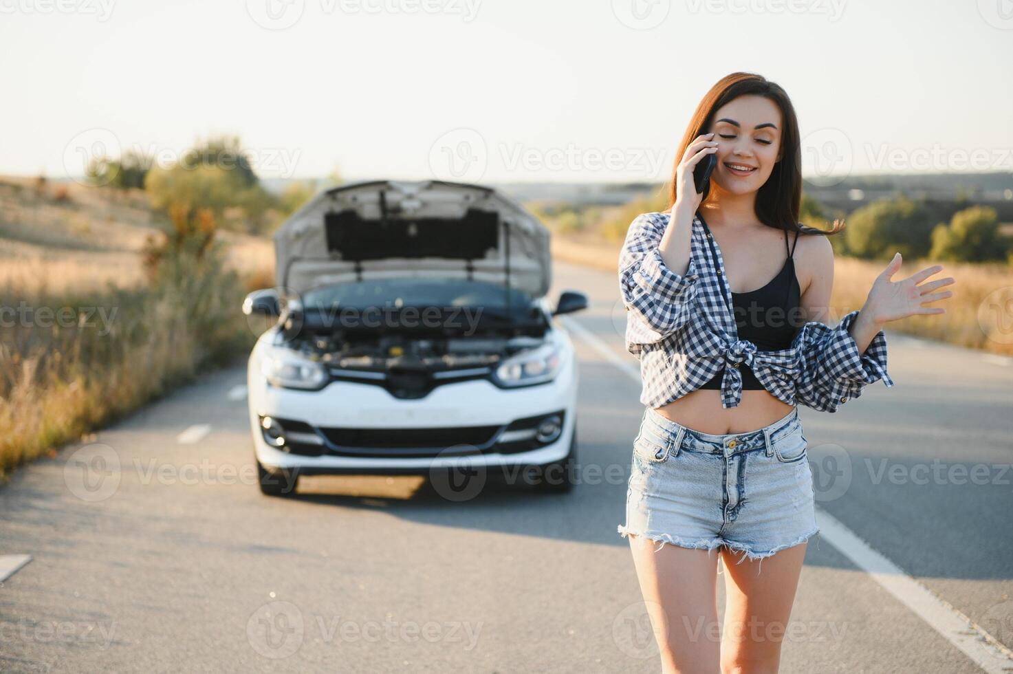 el joven niña rompió el coche y ella abrió el capucha y intentó a reparar el coche en el la carretera. un mujer llamadas en un teléfono inteligente con un coche evacuación Servicio foto