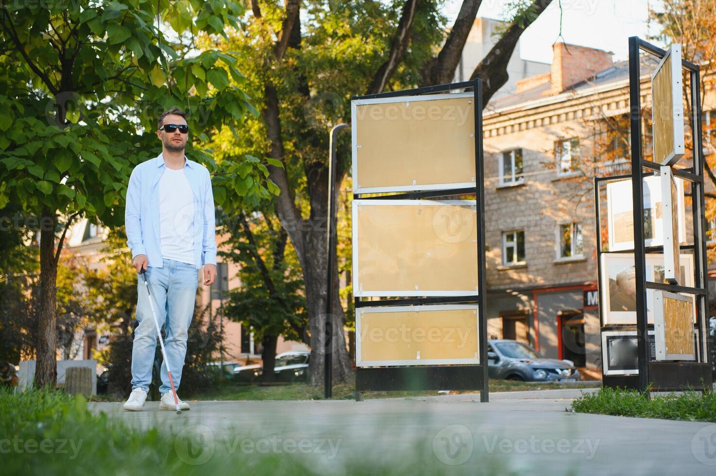 Young handsome blinded man walking with stick in town photo