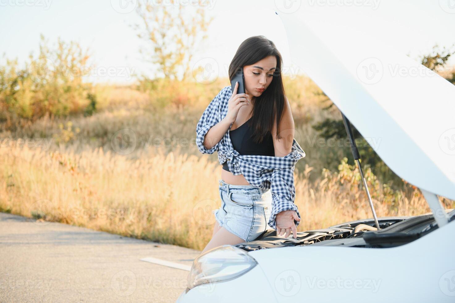 Young sexy woman with broken car calling on the cell phone. photo