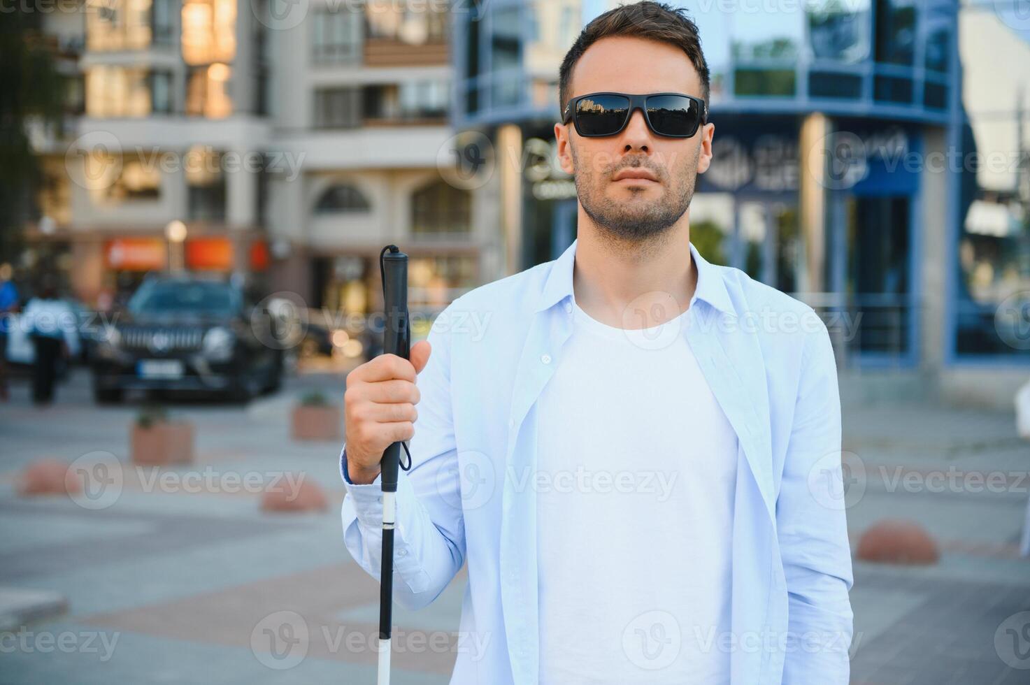 Portrait of a young, handsome blind man walking in the city. The concept of limited physical capabilities. photo