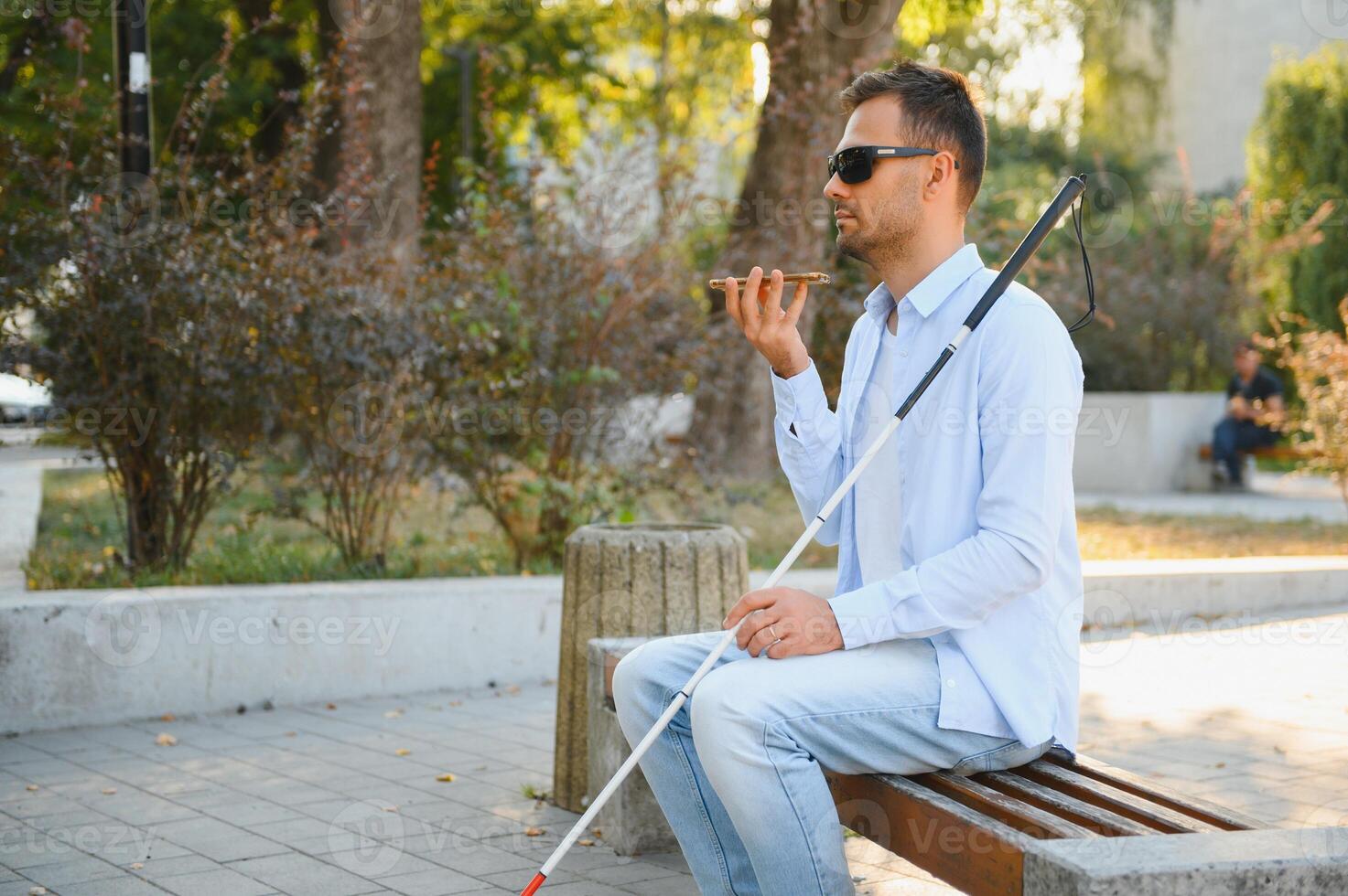 Young blinded man using phone and sending voice message photo