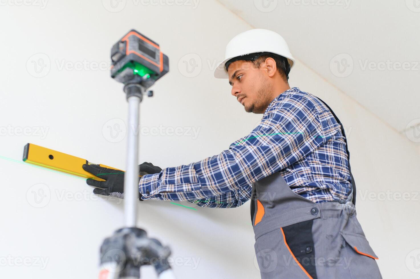 An Indian worker works in an empty apartment. A man in a uniform makes repairs inside the building photo