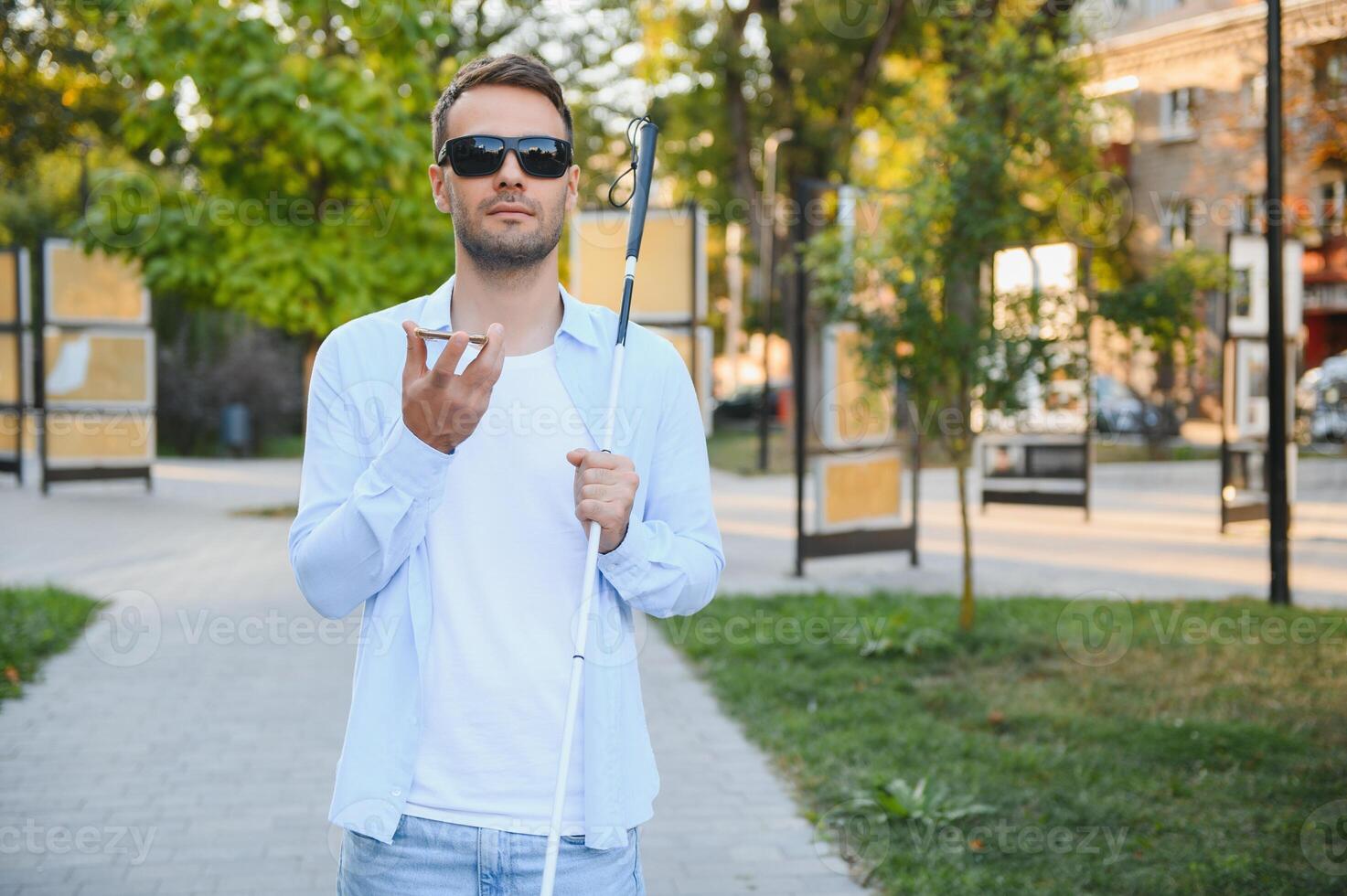 Young blinded man using phone and sending voice message photo