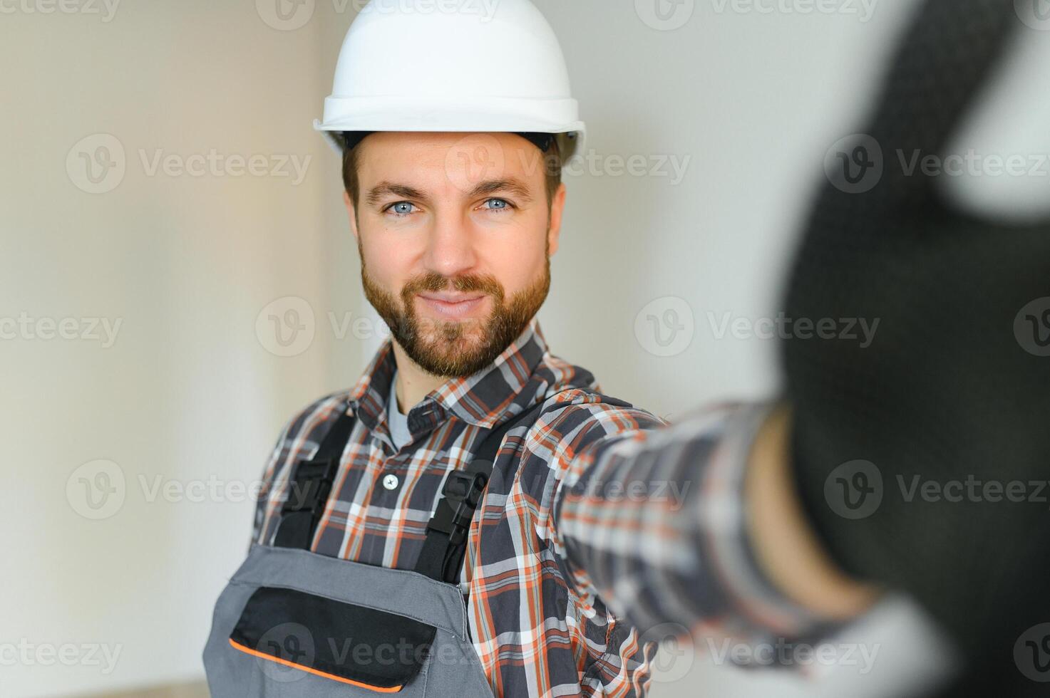 Portrait of positive, handsome young male builder while working at construction site. photo