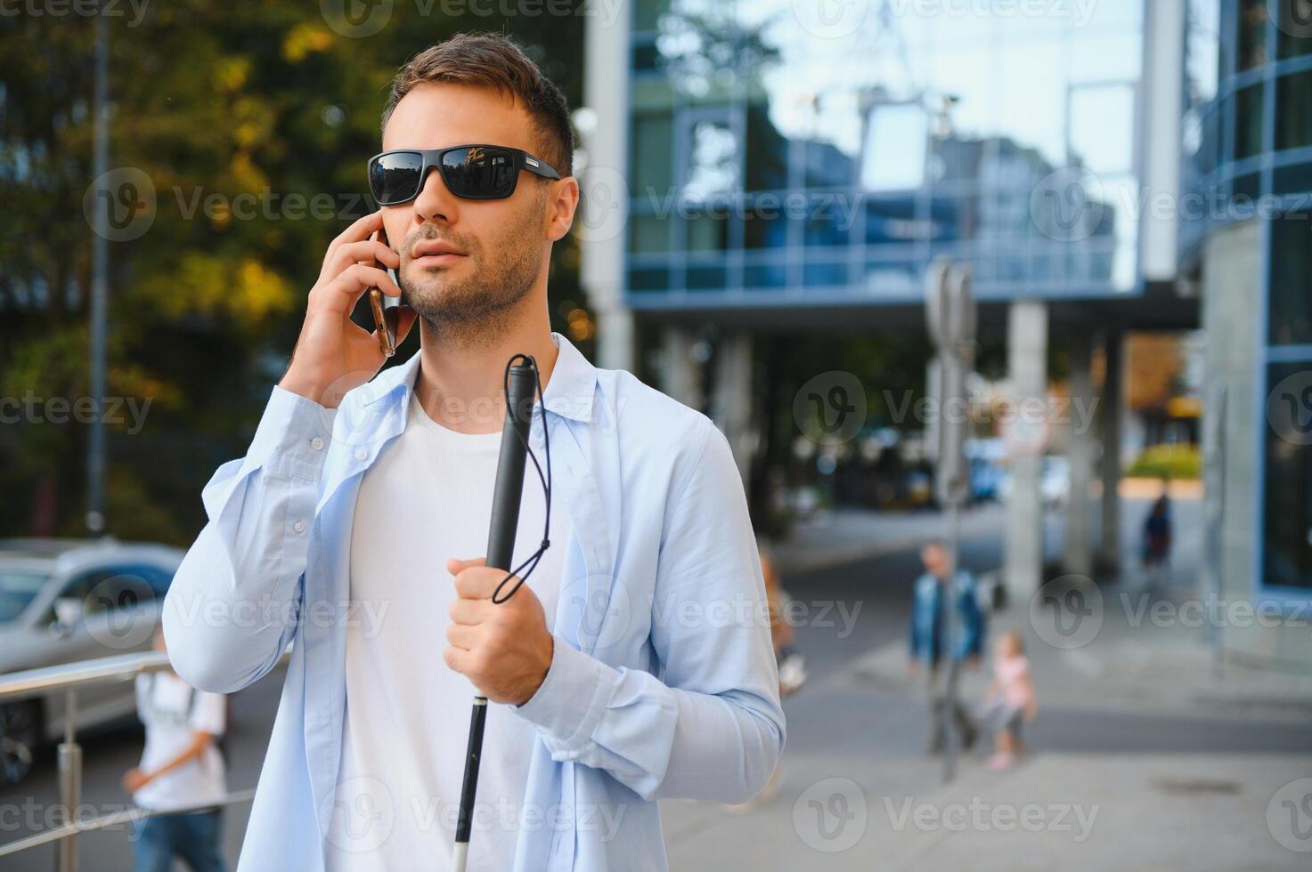 Young blinded man using phone and sending voice message photo