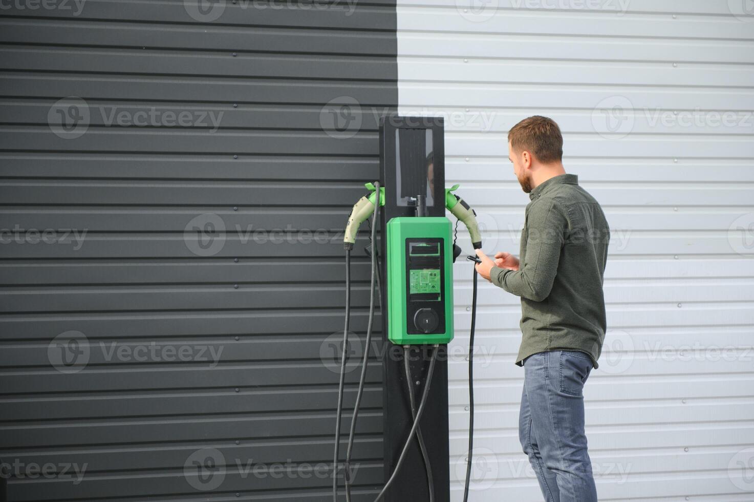 Man Holding Power Charging Cable For Electric Car In Outdoor Car Park photo