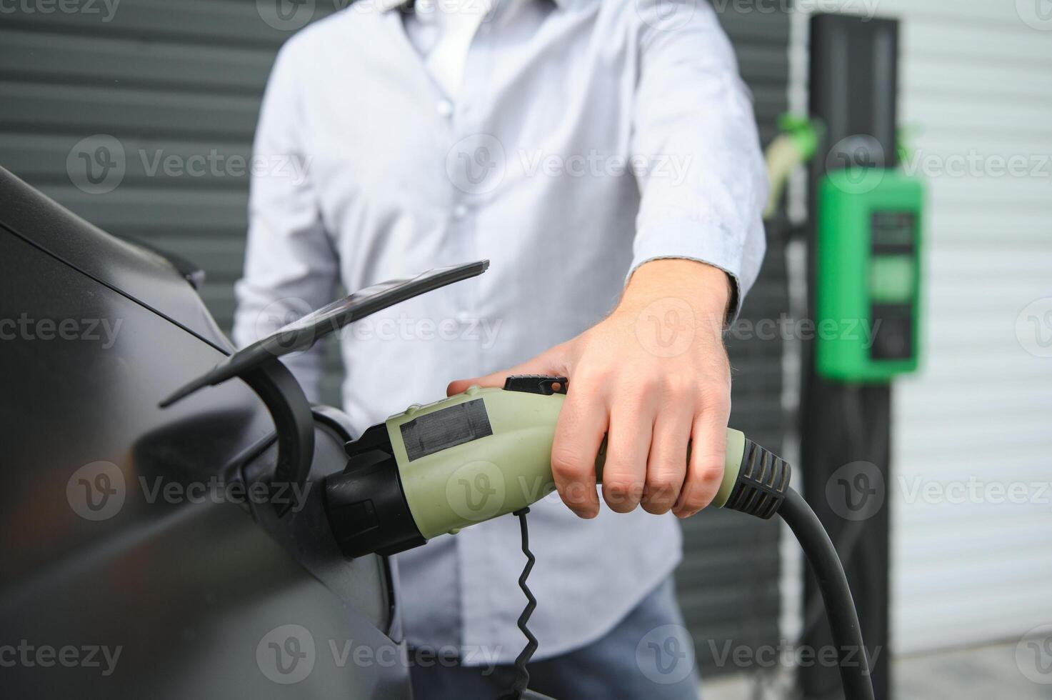 Man Holding Power Charging Cable For Electric Car In Outdoor Car Park photo