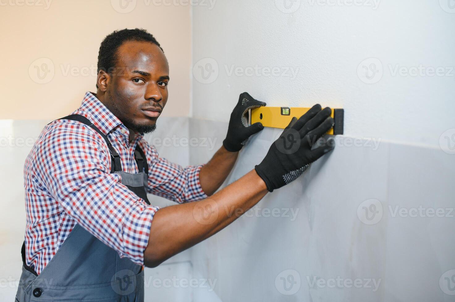 African American Worker installing wall tile with vacuum holder indoors photo