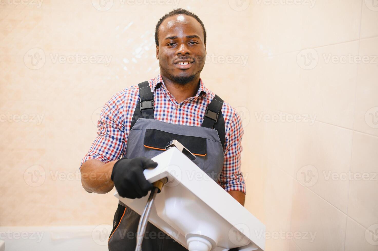 de cerca de contento joven africano masculino fontanero reparando lavabo en baño foto