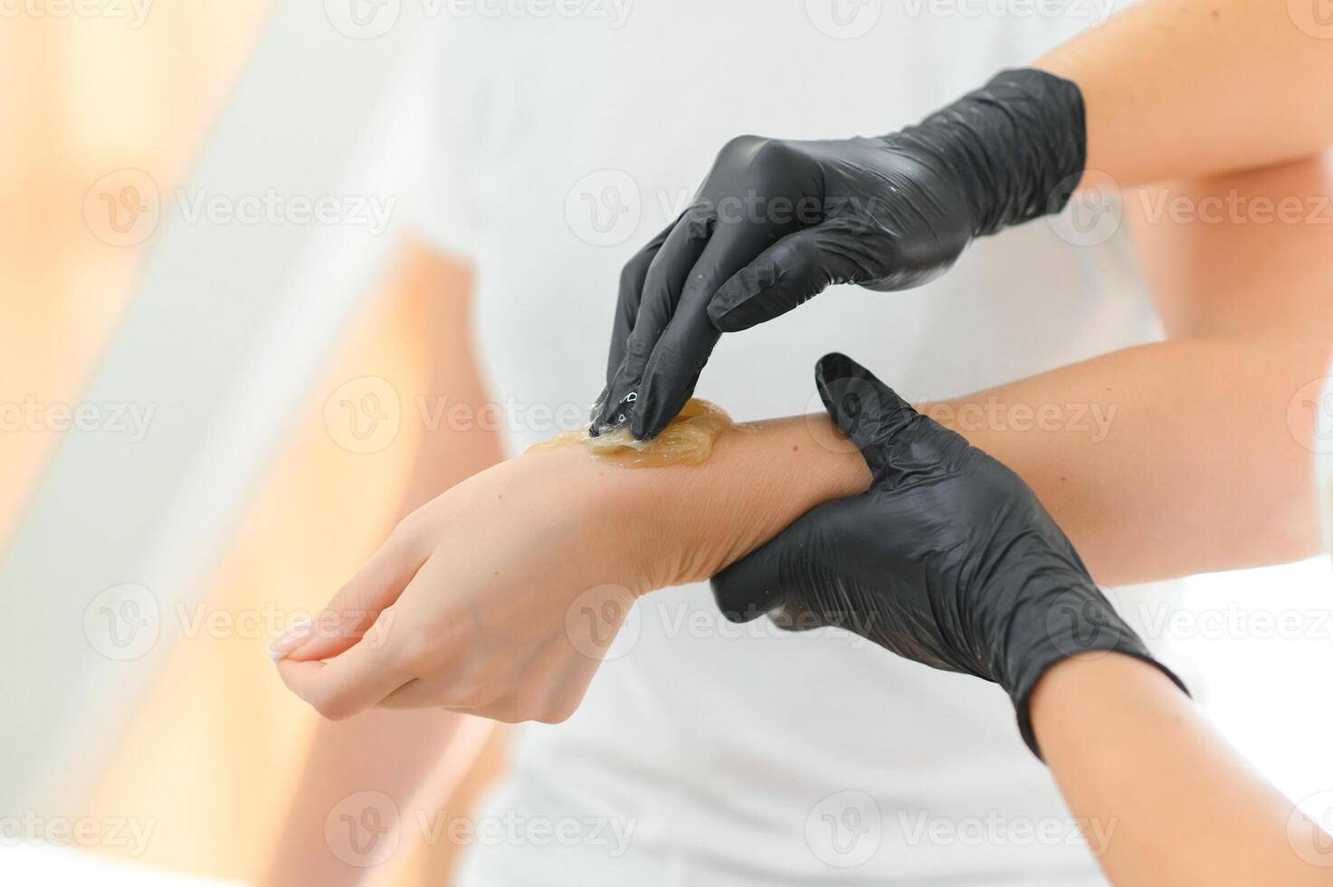 Sugar paste hair removal procedure - shugaring. Cosmetologist applies sugar paste to the hand photo