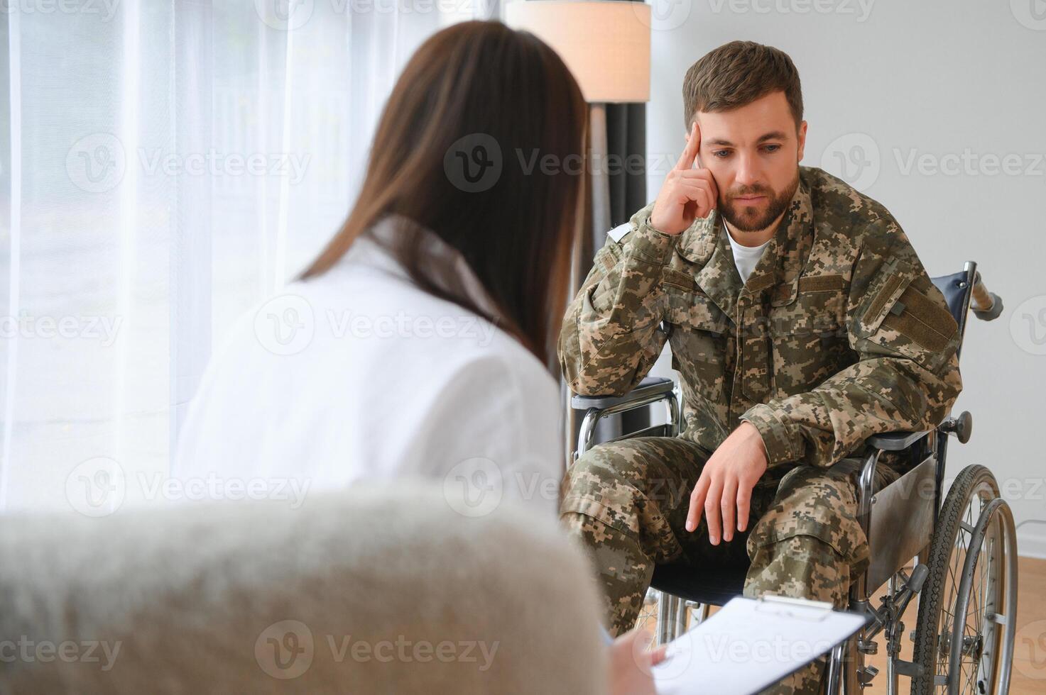 Deprimido chico en camuflaje uniforme paralizado soldado en silla de ruedas visitando hembra psicólogo. foto