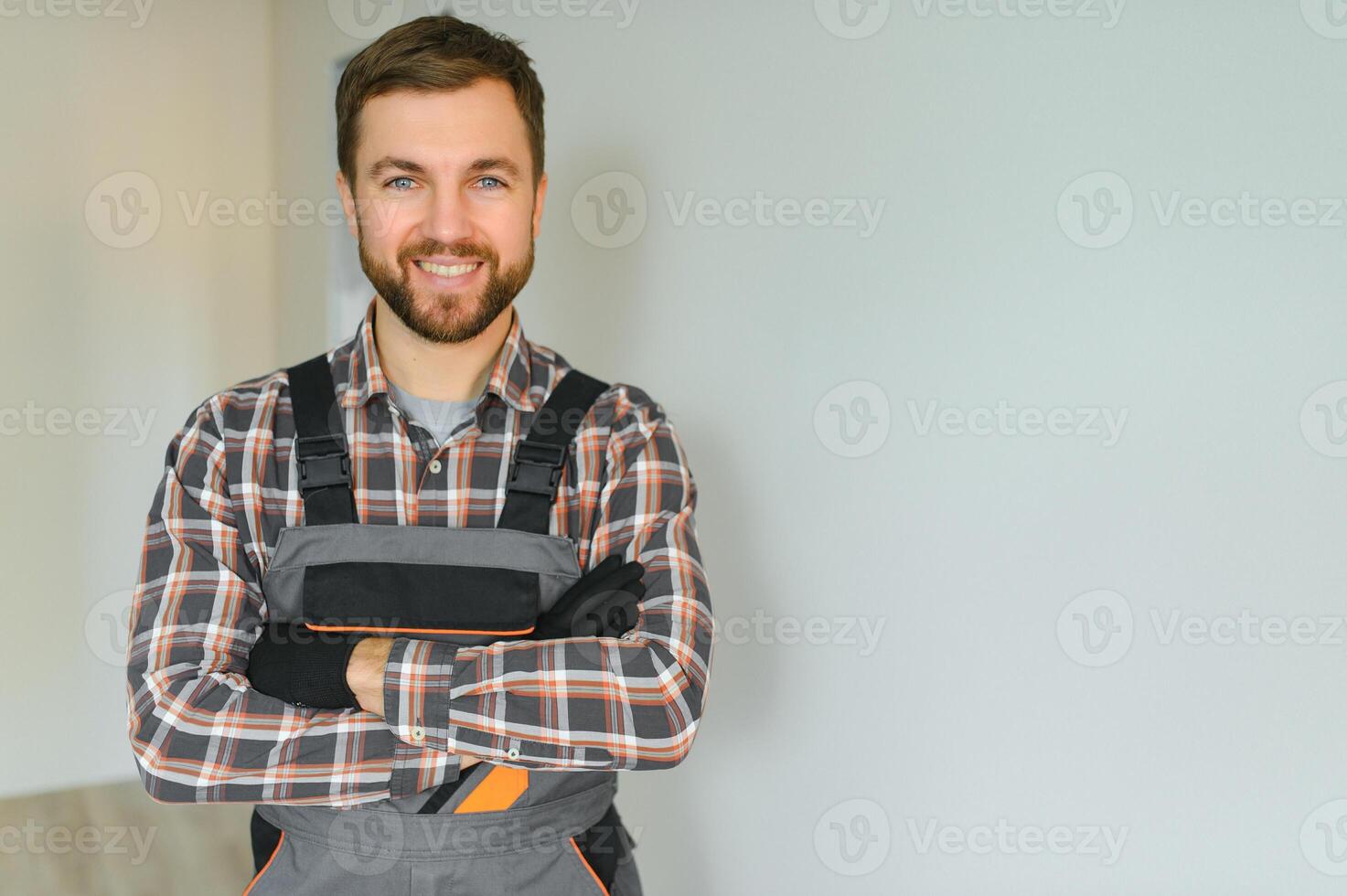 Portrait of positive, handsome young male builder while working at construction site. photo