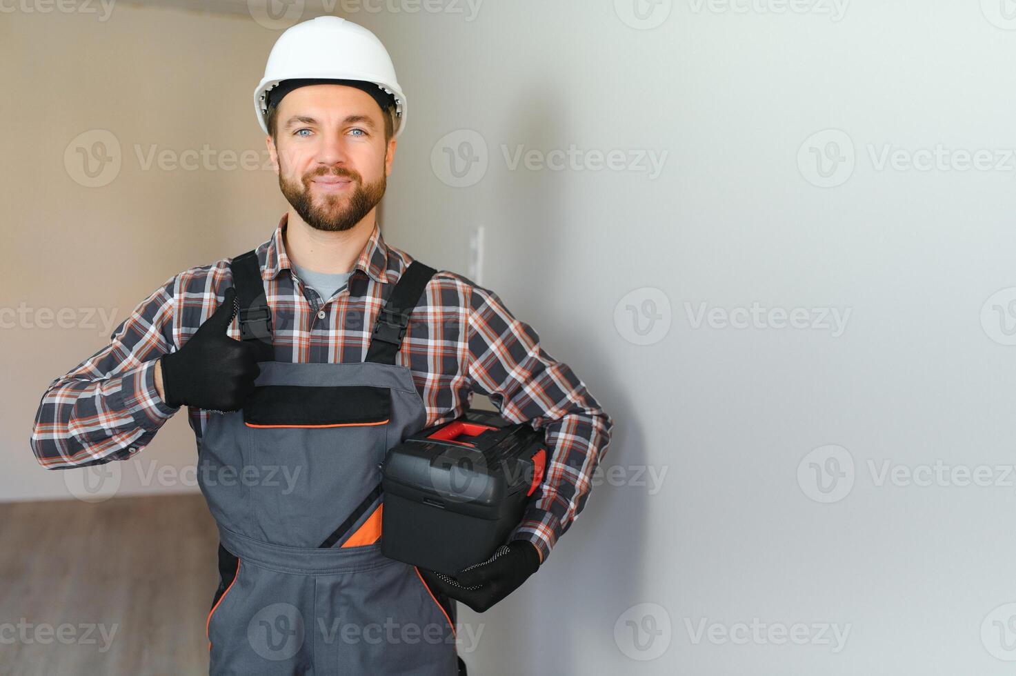 Portrait of a confident repairman with beard standing in empty apartment photo