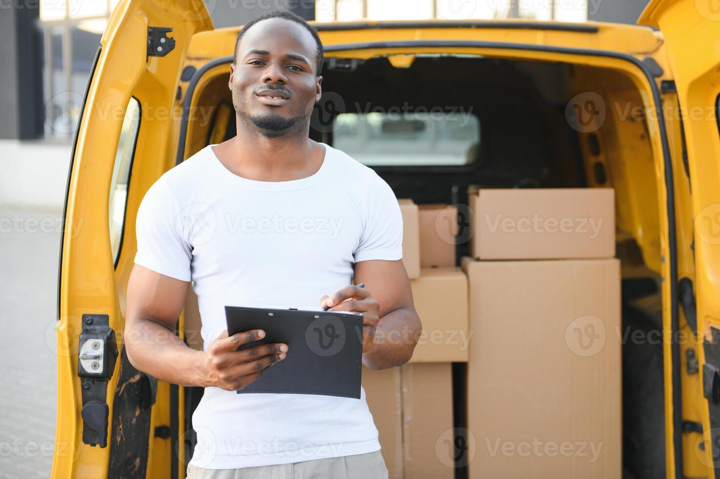 african male postal delivery courier man in front of car delivering package photo