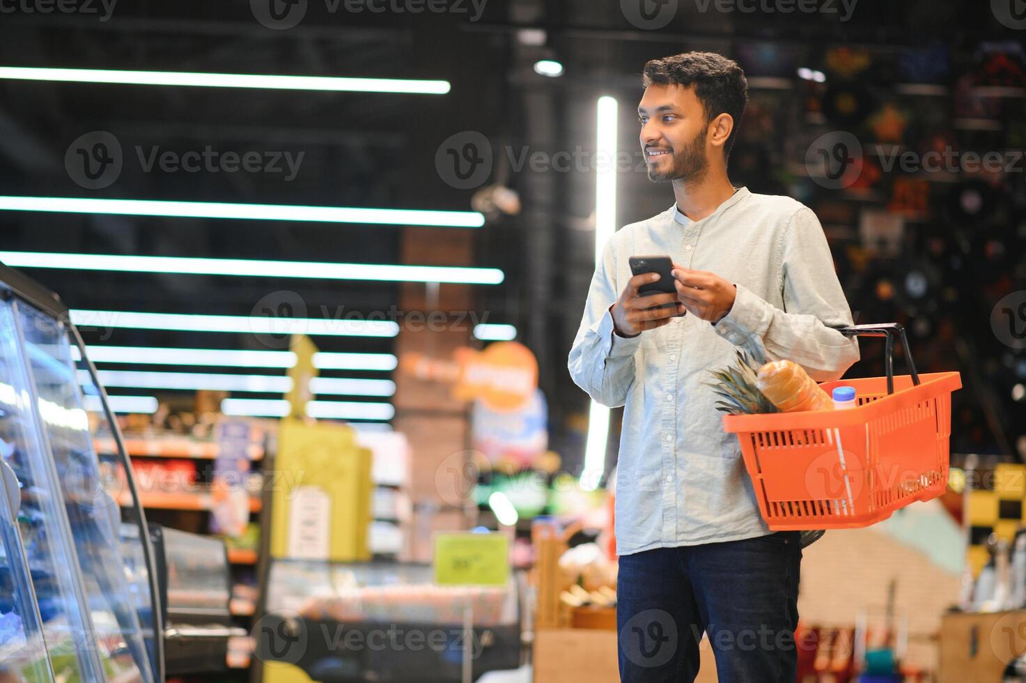 indio hombre utilizando teléfono inteligente a tienda de comestibles tienda. foto