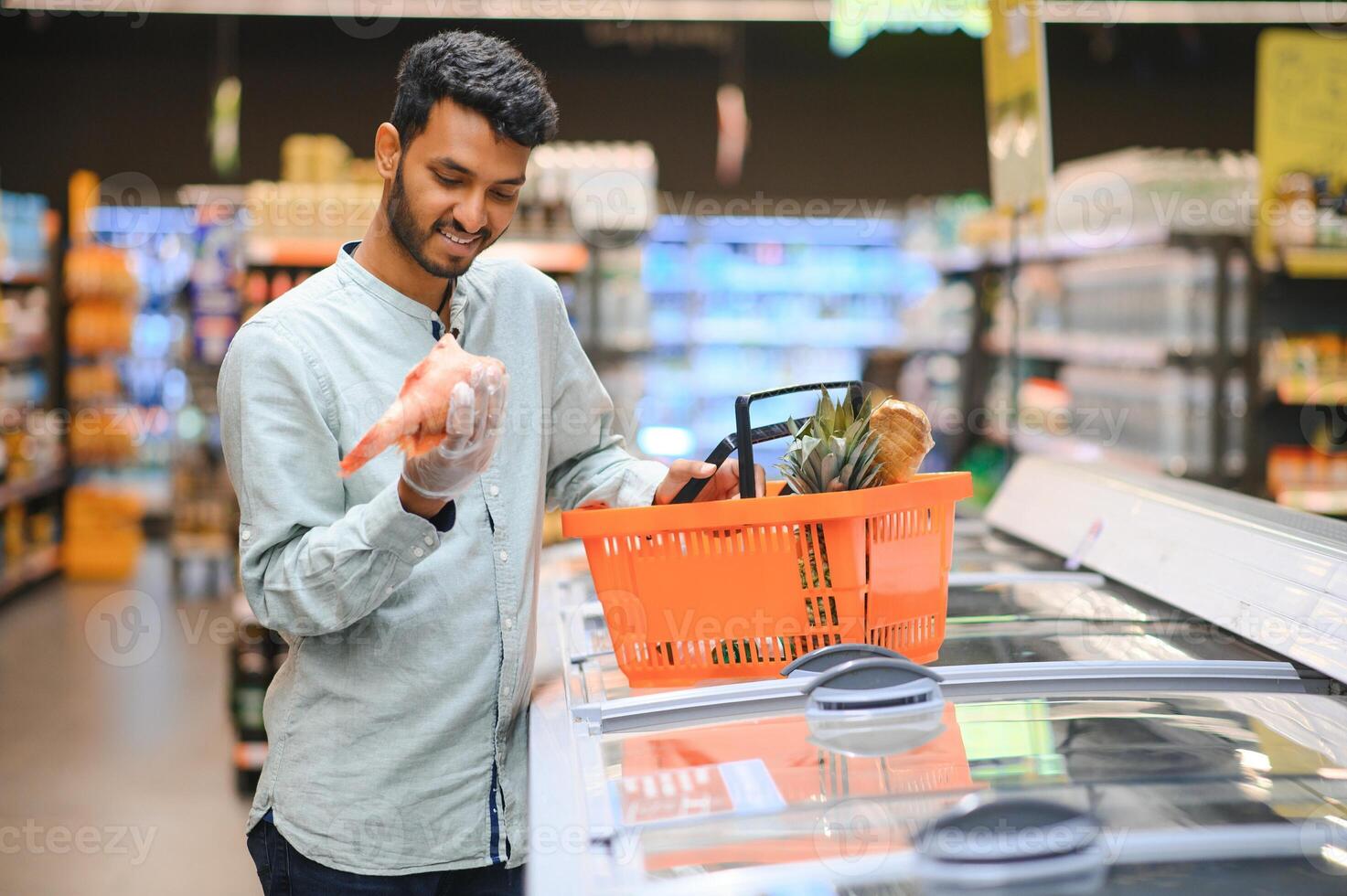 Portrait of happy Indian man standing in front of the product counter in a grocery store. Man buying grocery for home in supermarket. photo