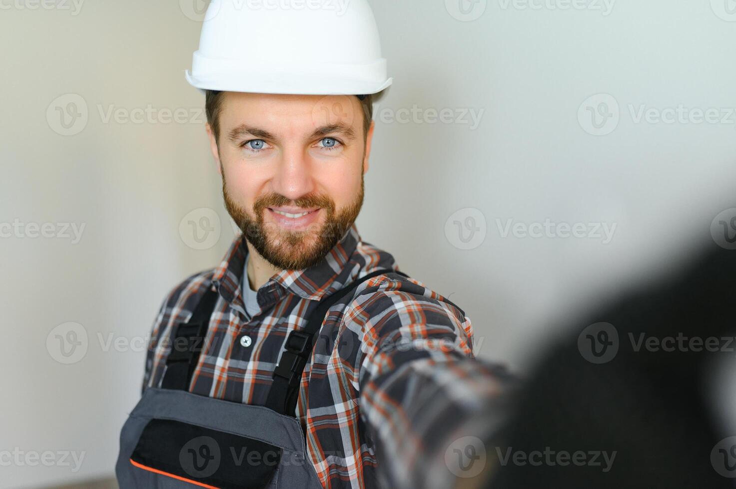 Portrait of positive, handsome young male builder while working at construction site. photo