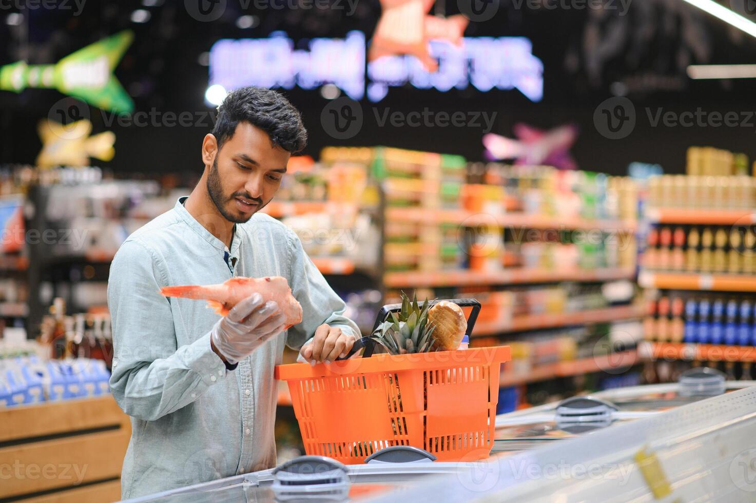 Portrait of handsome young Indian man standing at grocery shop or supermarket, Closeup. Selective Focus. photo