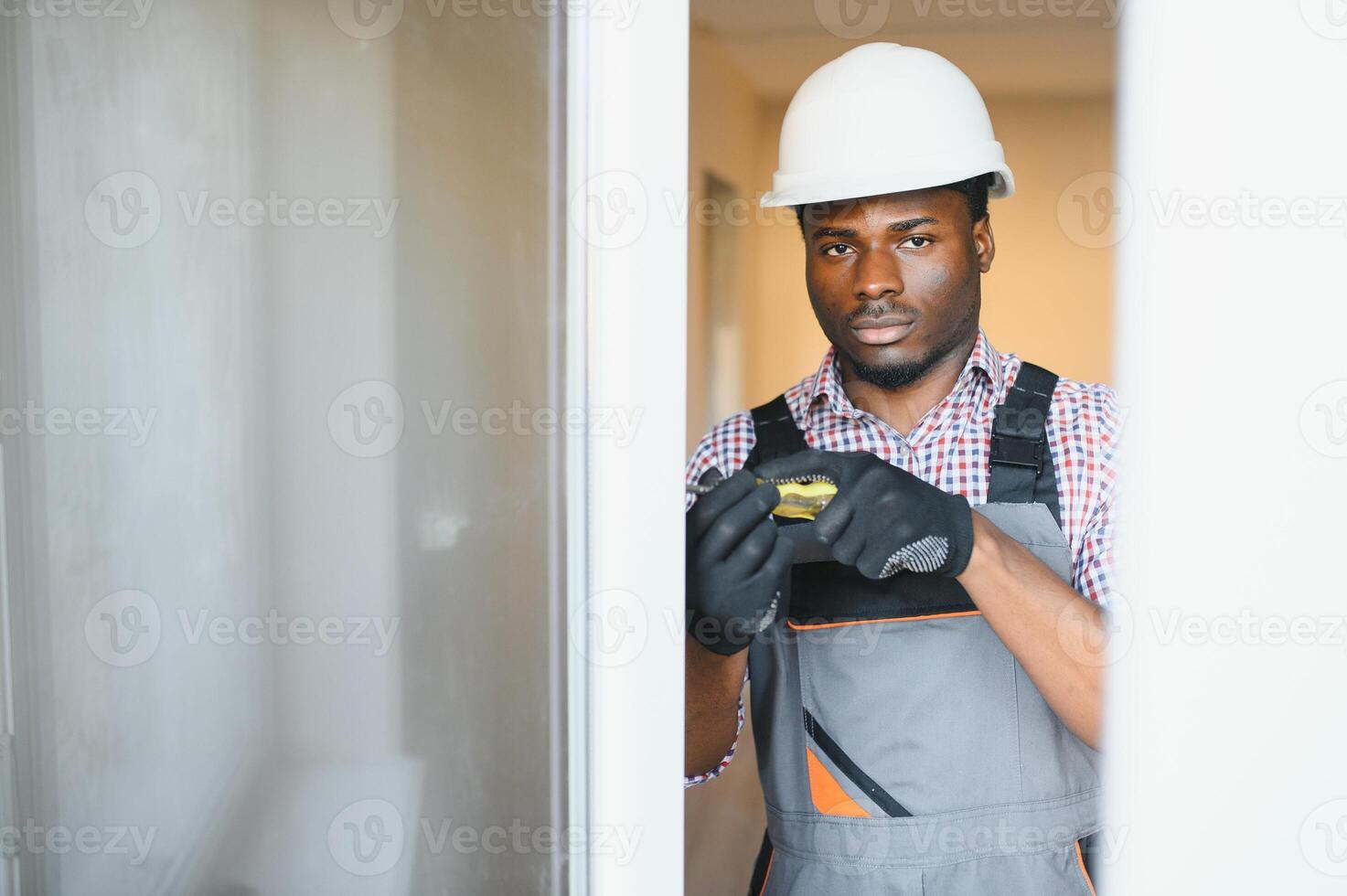 Close-up Of Young African Handyman In Uniform Installing Window photo