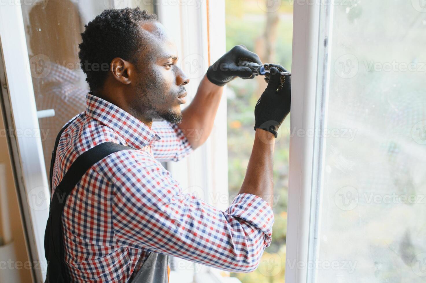 Close-up Of Young African Handyman In Uniform Installing Window photo