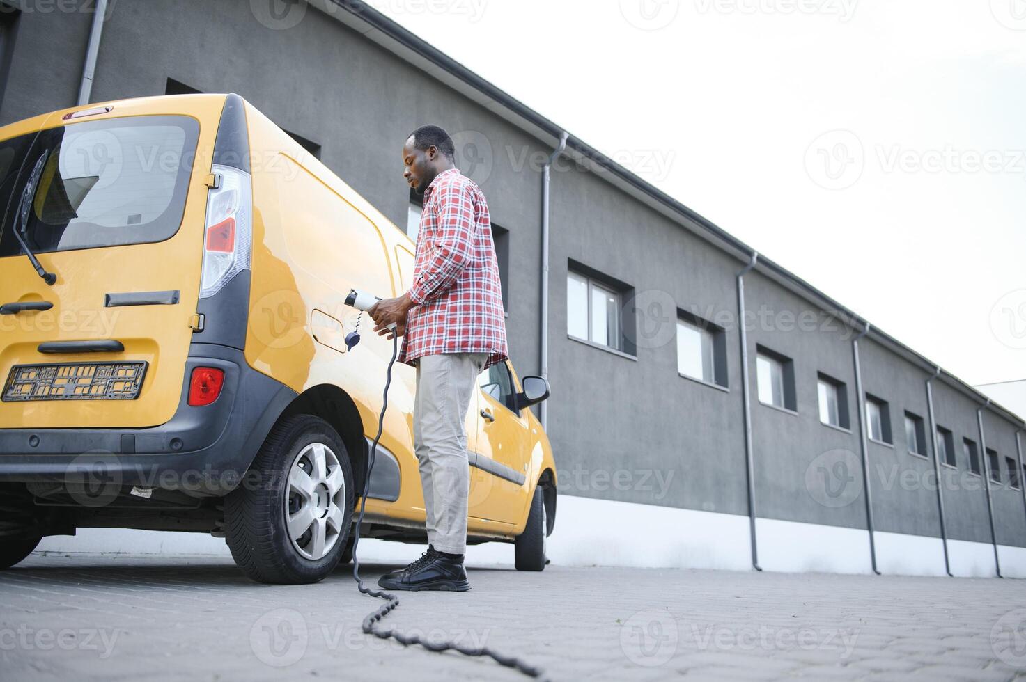 Stylish man inserts the charging cable into the socket of electric car photo