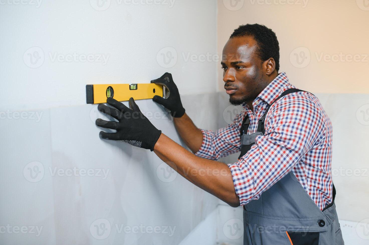 African American Worker installing wall tile with vacuum holder indoors photo