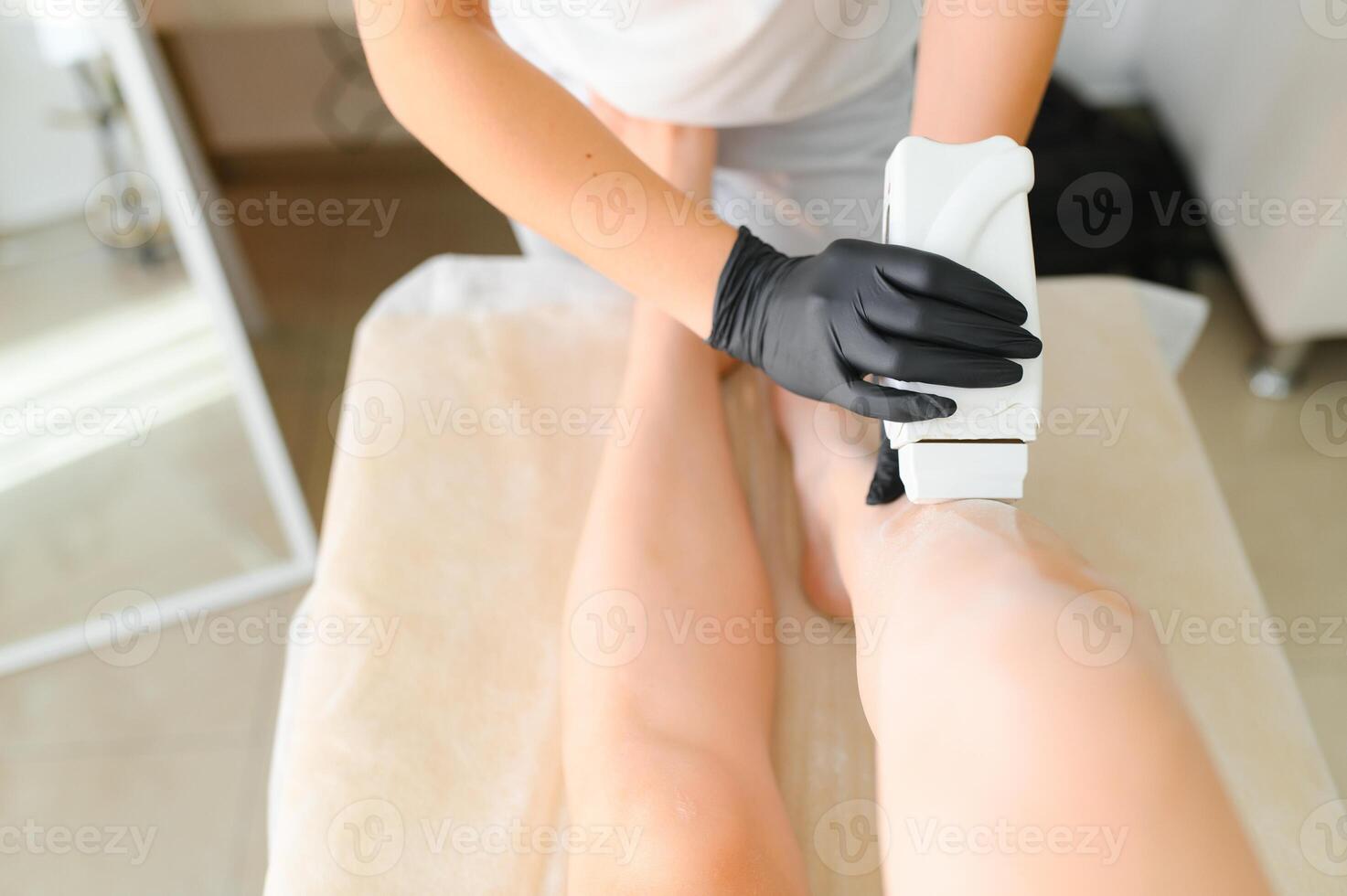 Beautician waxing female legs in spa center photo