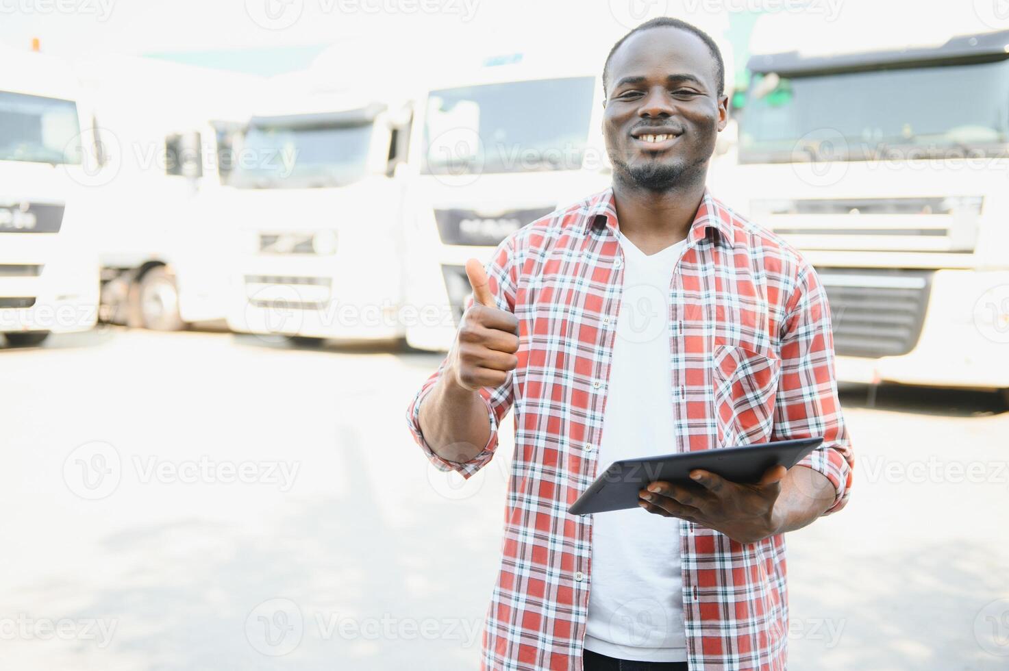 Truck driver checking shipment list while standing on parking lot of distribution warehouse photo