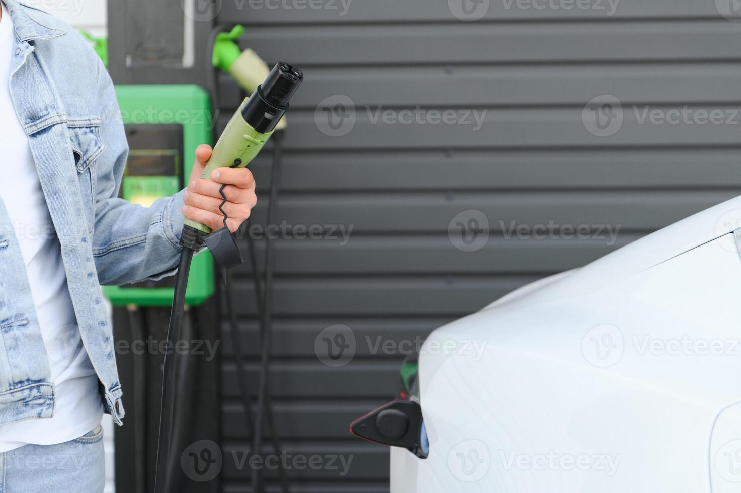 Close Up Of Hand Holding Power Cable For Environmentally Friendly Zero Emission Electric Car photo