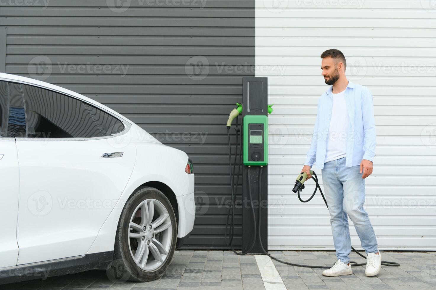 a man charges an electric car photo