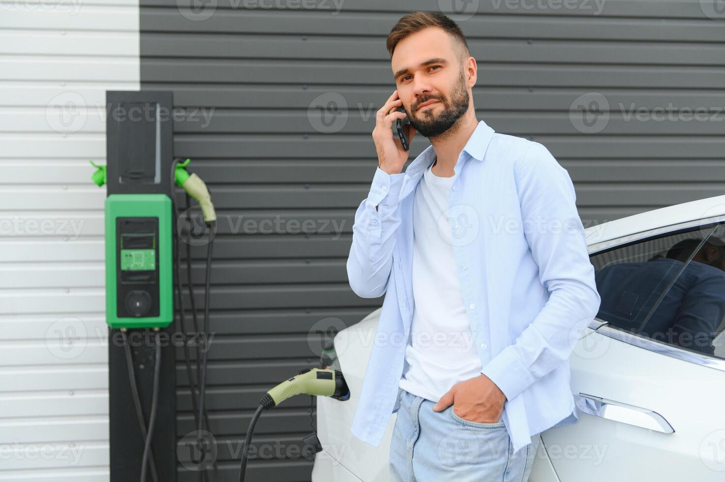 hombre en pie por su eléctrico coche foto