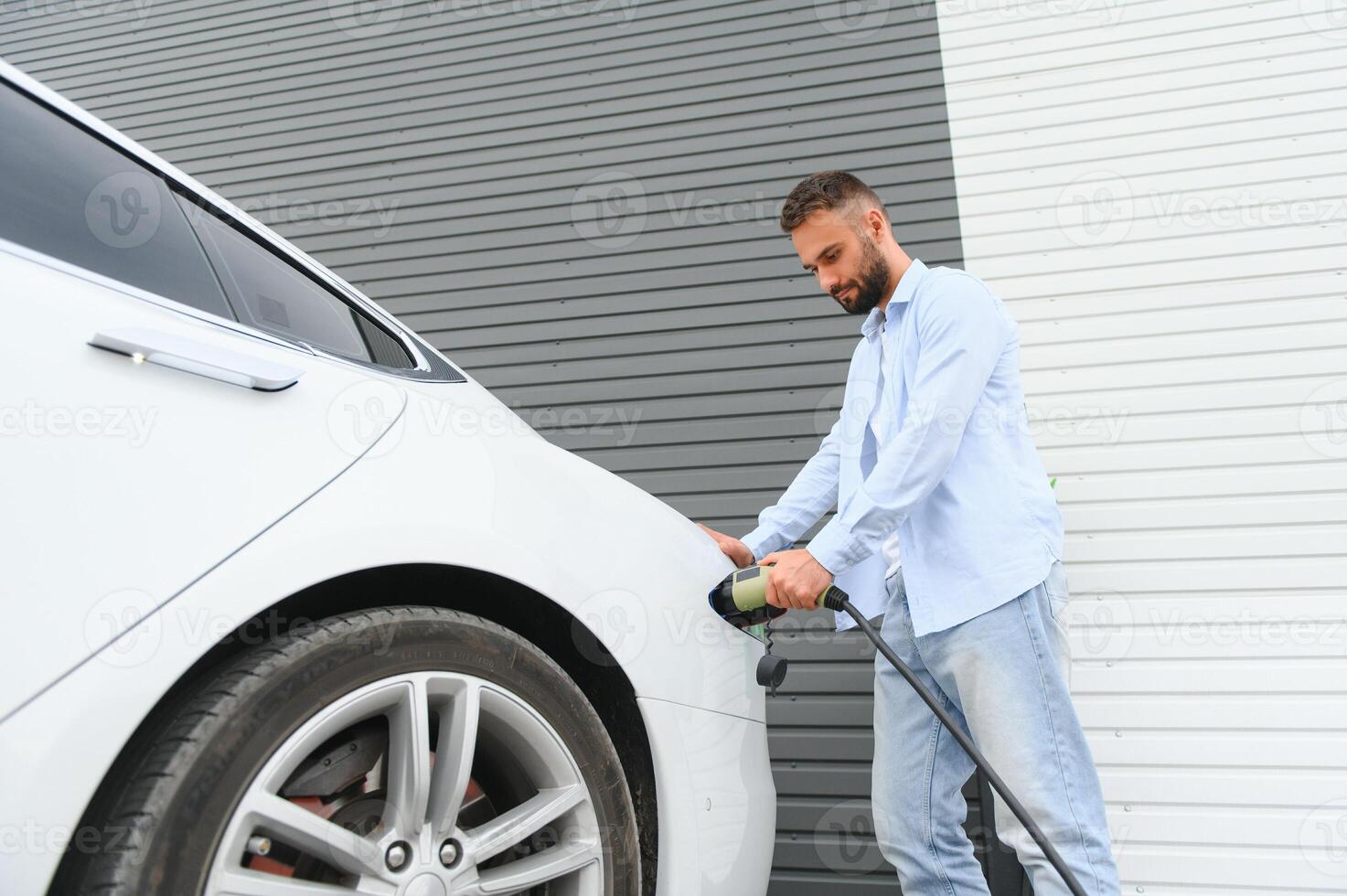 hombre en pie por su eléctrico coche foto