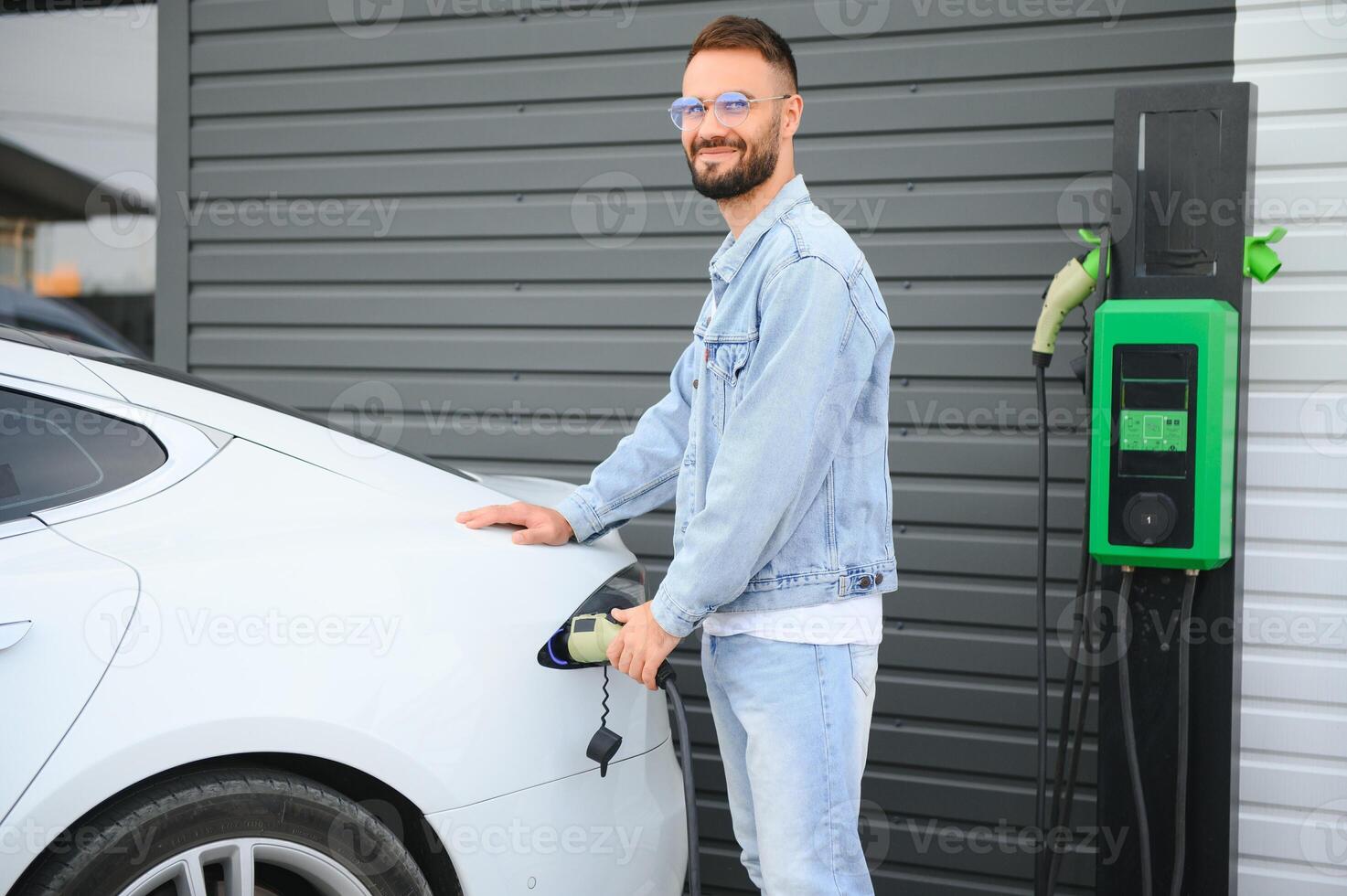 hombre en pie por su eléctrico coche foto