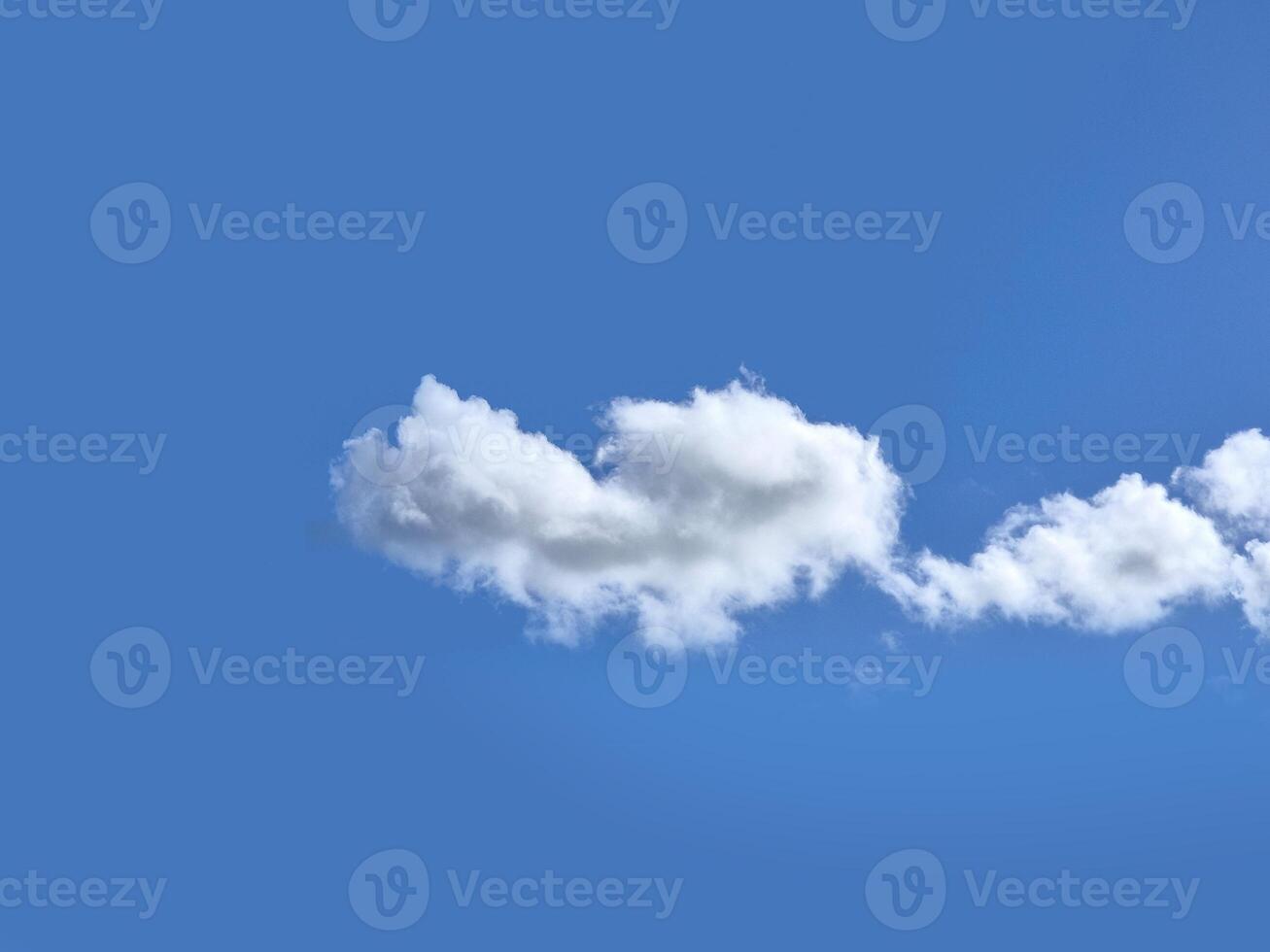 Single white fluffy cumulus cloud in the blue summer sky photo